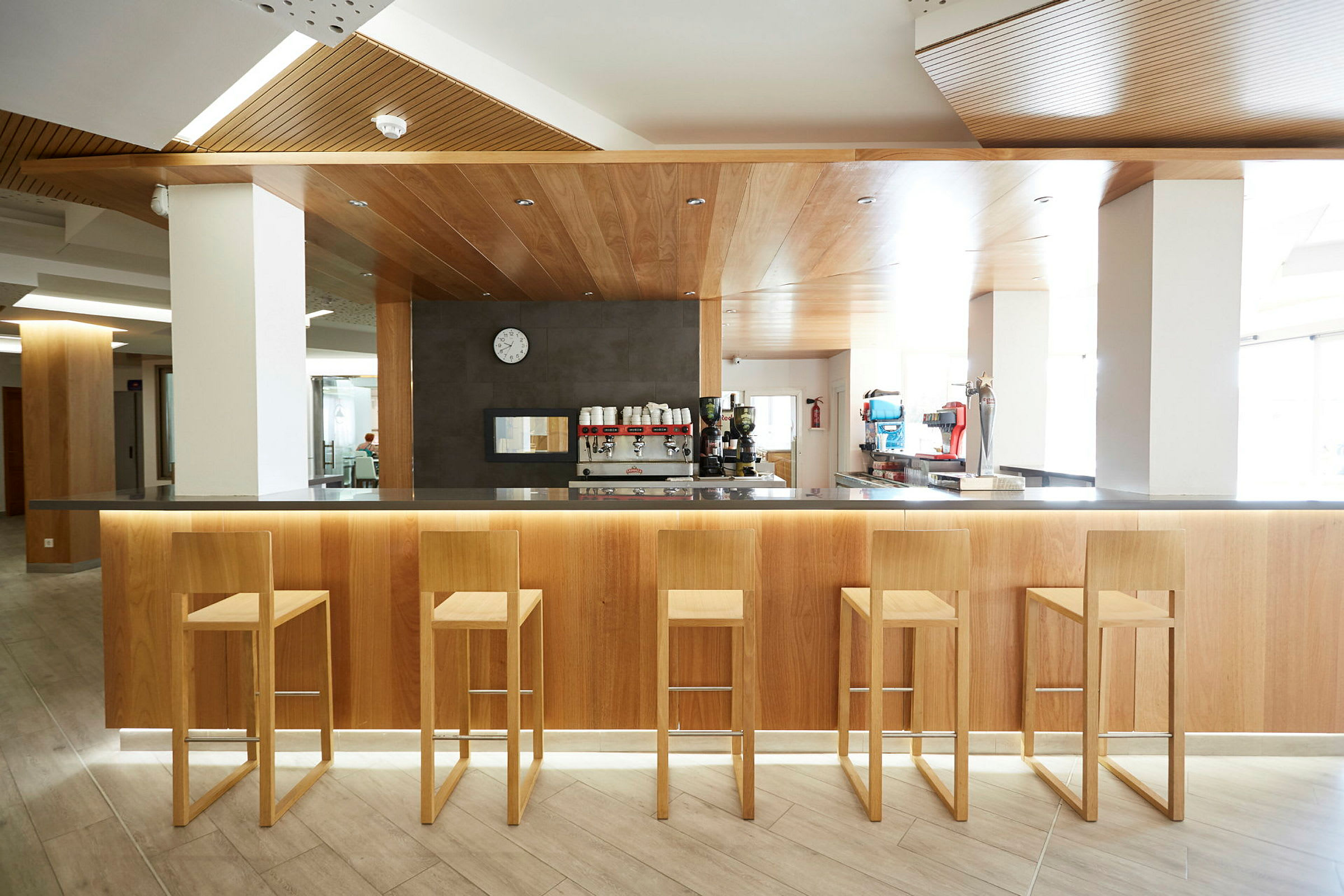 Interiørbilde av en moderne bar med fem trestoler foran en bardisk i tre. (AI-generert tekst)