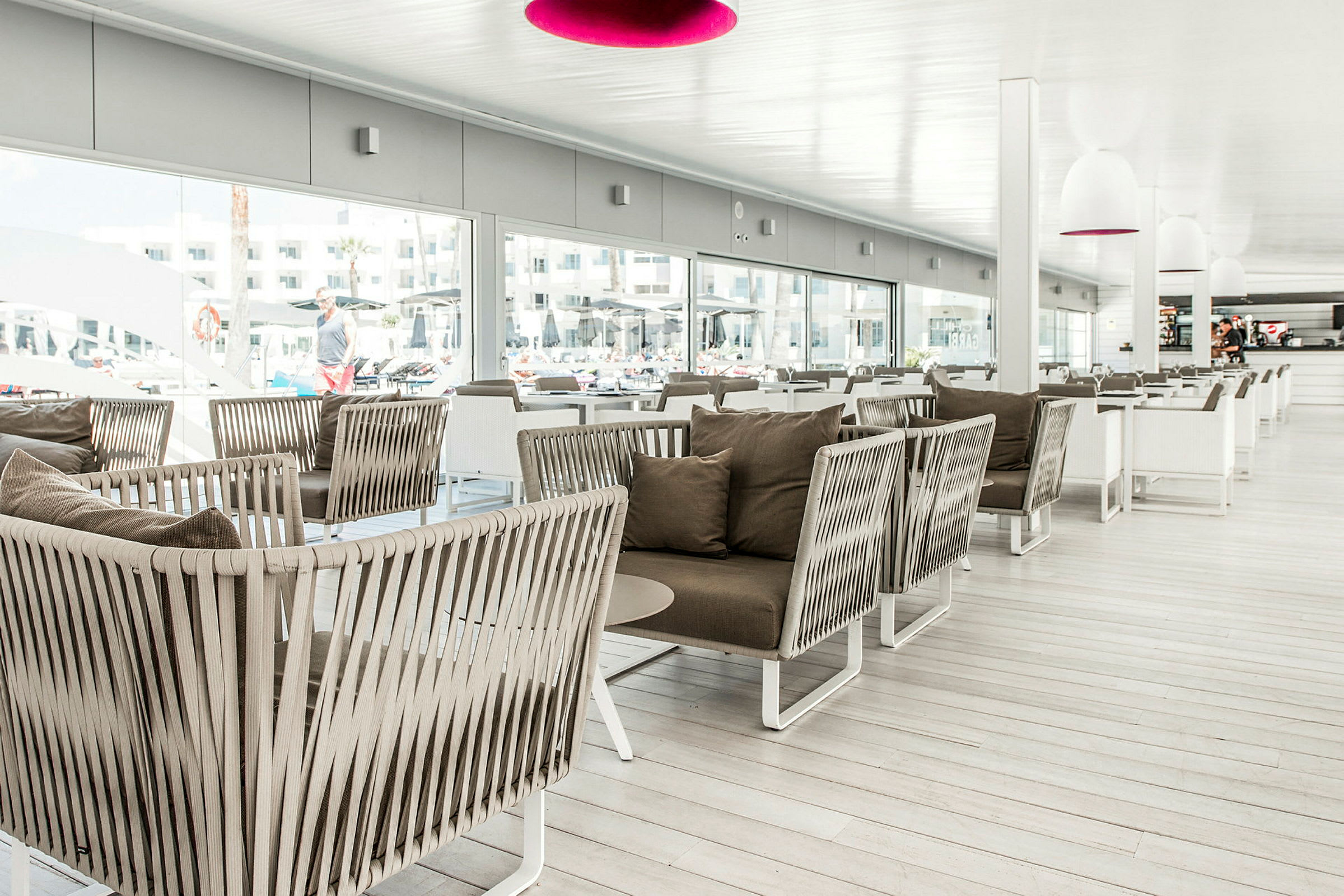 En moderne innendørs lounge med komfortable rottingstoler og bord. (AI-generert tekst)