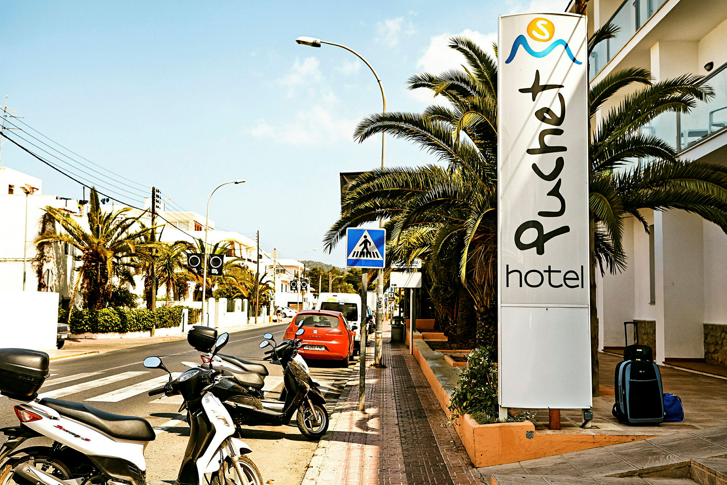 Gate med parkerte motorsykler og et skilt som viser "Puchet Hotel". (AI-generert tekst)