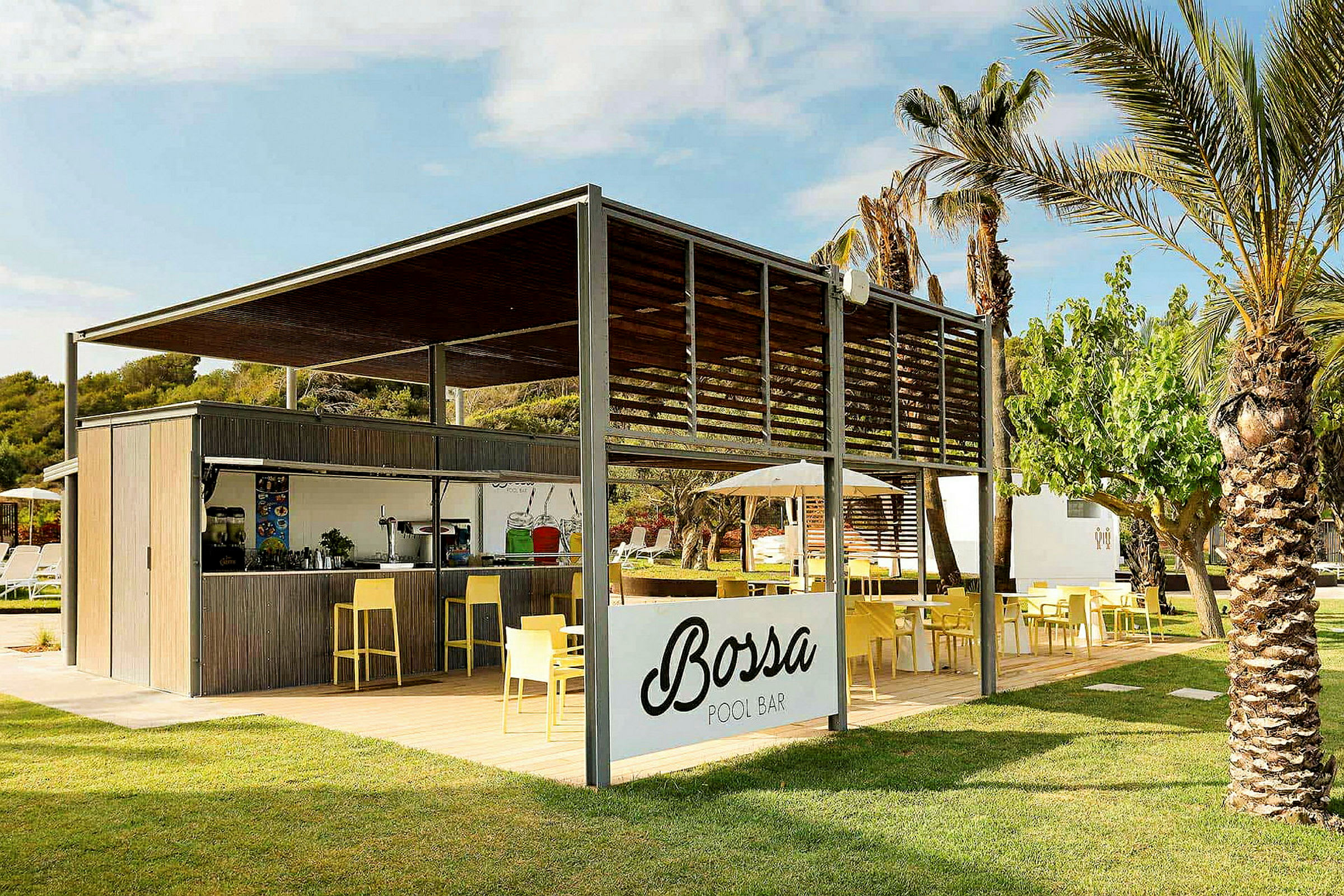 En utendørs bassengbar med skiltet 'Bossa Pool Bar', omgitt av grøntområder og palmer. Det finnes sitteplasser med gule stoler og bord. (AI-generert tekst)