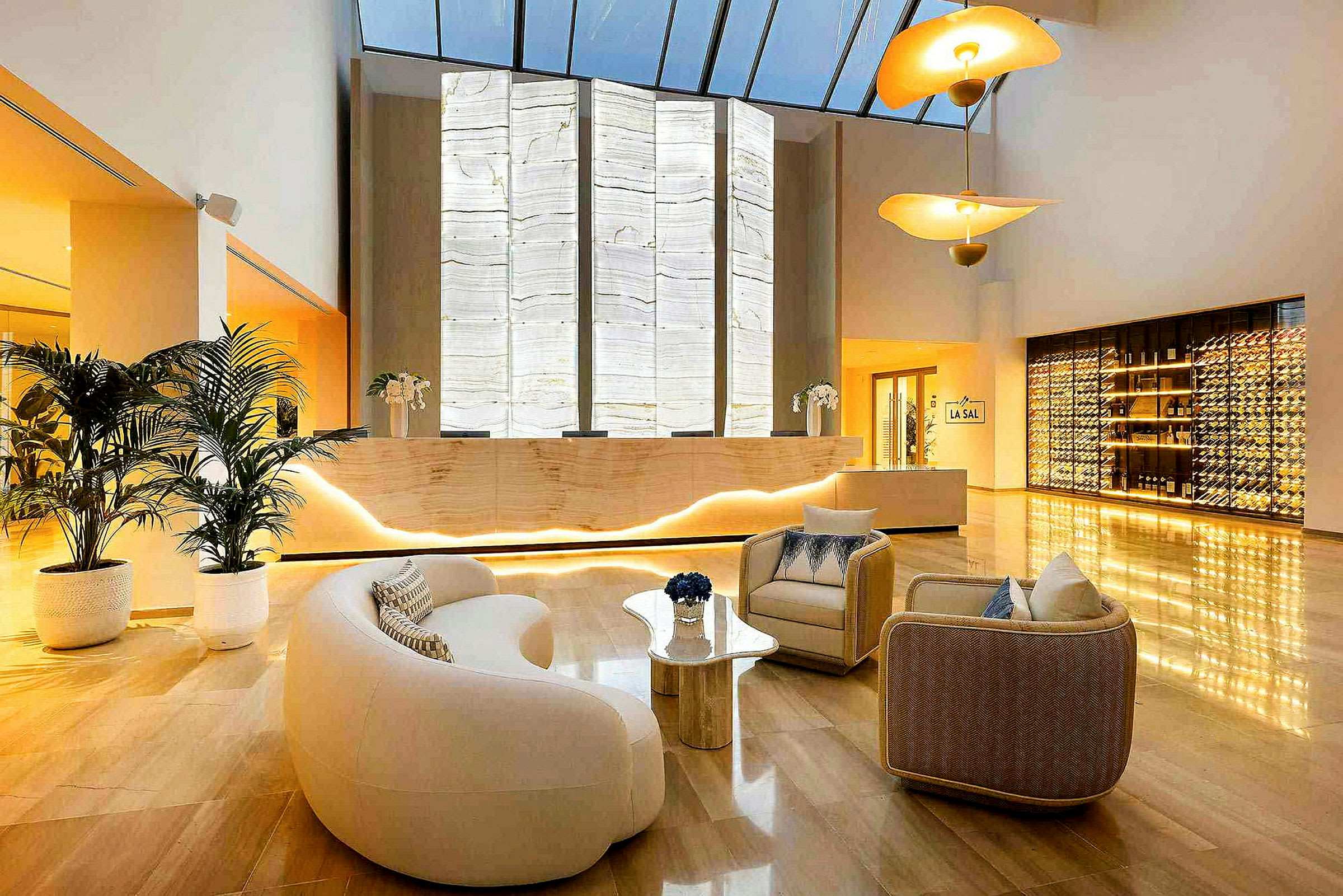 En moderne hotellobby med lenestoler, en resepsjon med bakgrunnsbelyst vegg, og en vinoppbevaringsdisplay. (AI-generert tekst)