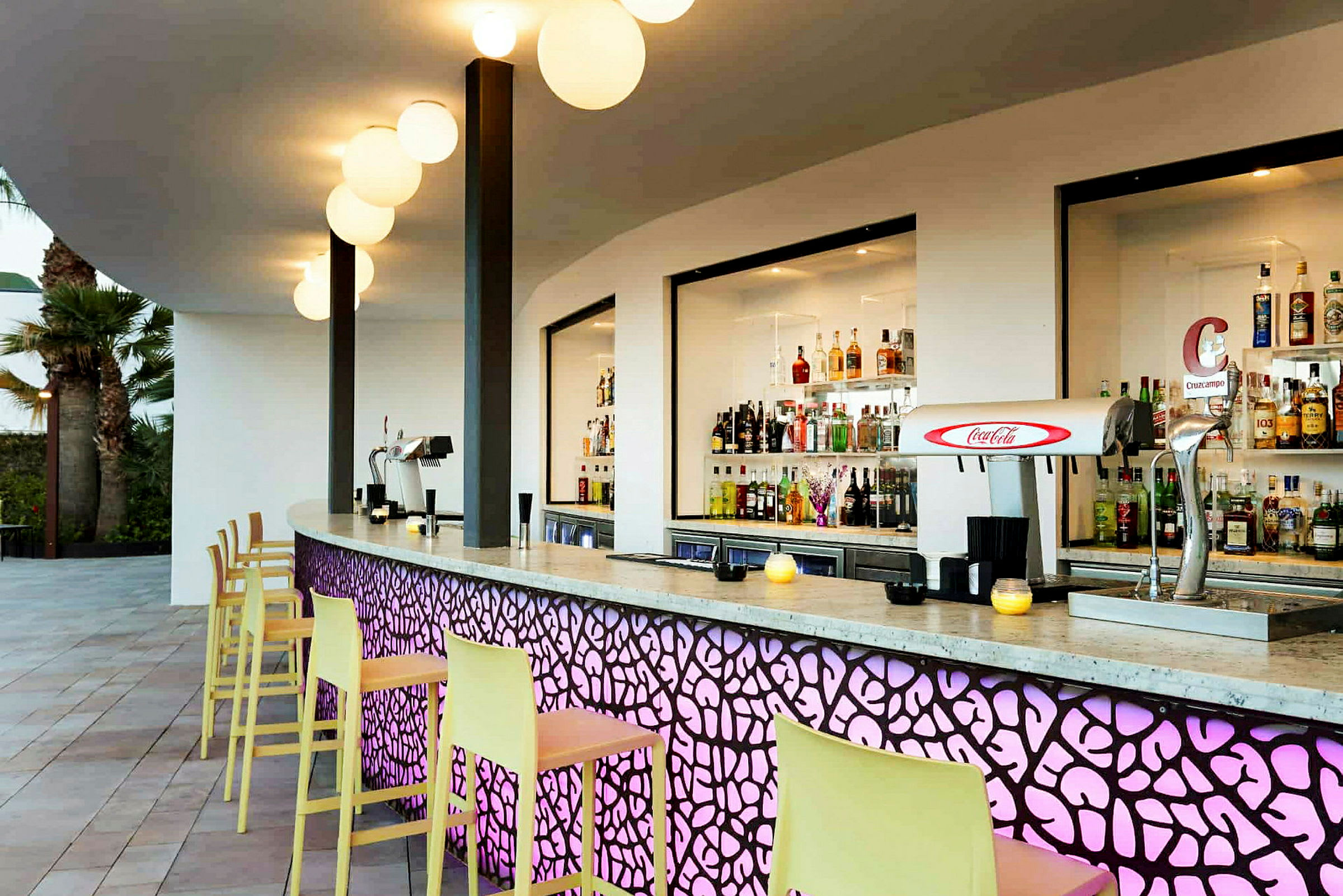En moderne bar med fargerike detaljer og et utvalg av drikkevarer bak disken. (AI-generert tekst)