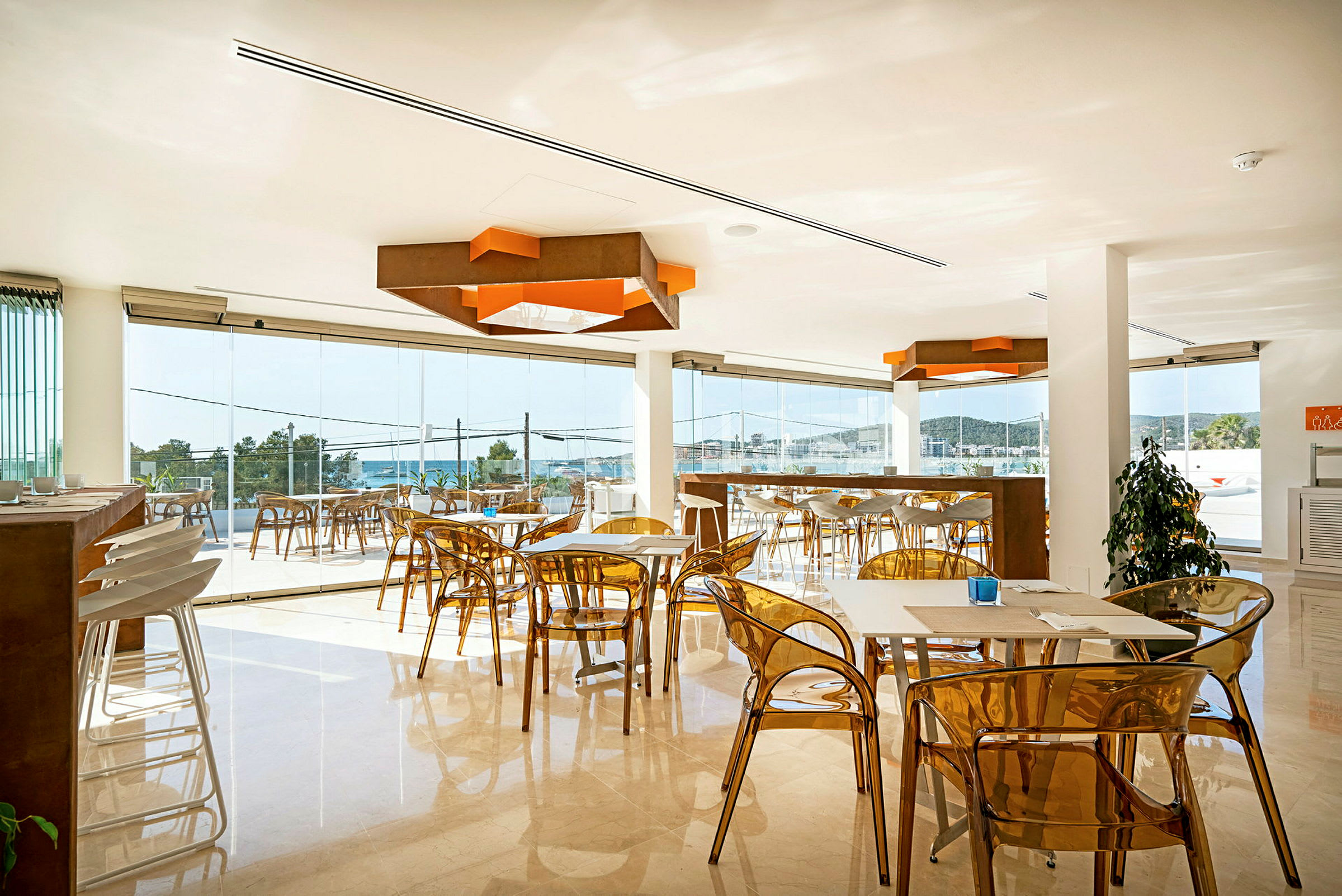 En moderne kafé med gjennomsiktige stoler og vinduer med utsikt over havet. (AI-generert tekst)