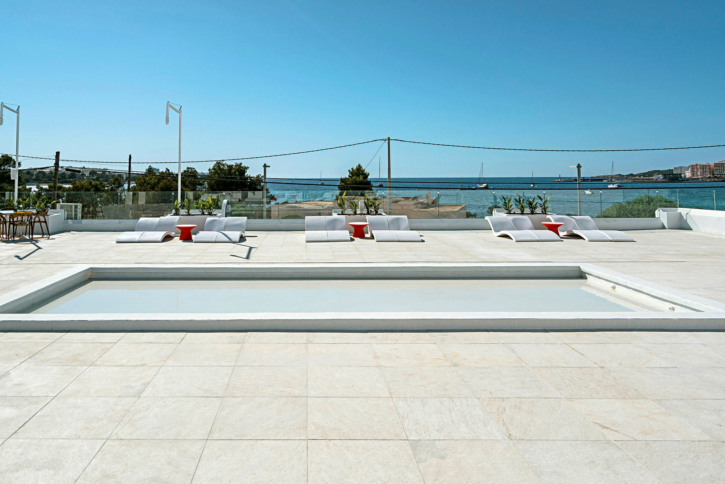 Solterrasse med basseng, solsenger og utsikt over havet. (AI-generert tekst)
