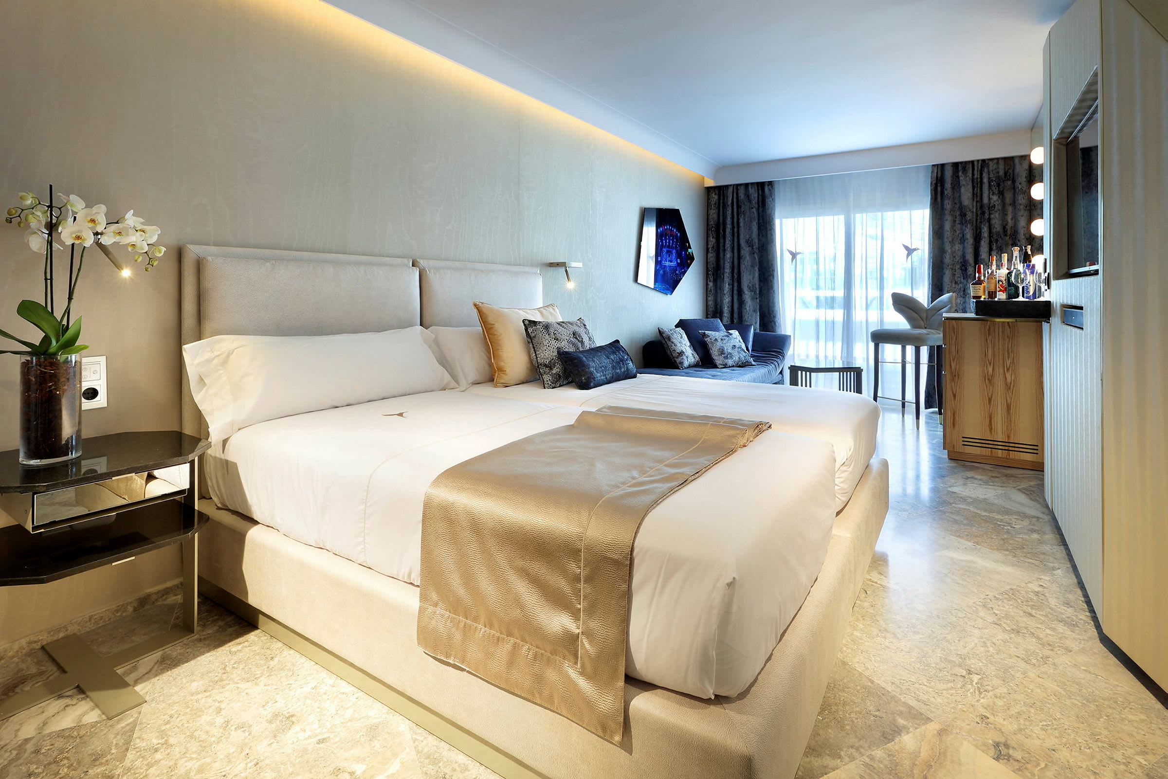 Et moderne hotellrom med en stor seng, sofagruppe og en minibar foran et stort vindu. (AI-generert tekst)