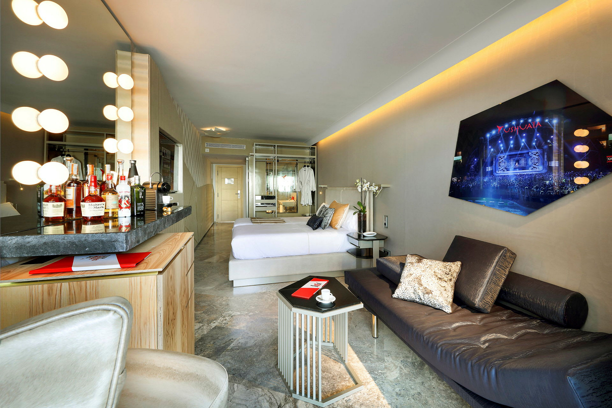 Bilde av et hotellrom med moderne design, inkludert en komfortabel seng, minibar, sofa og vegg-TV. (AI-generert tekst)