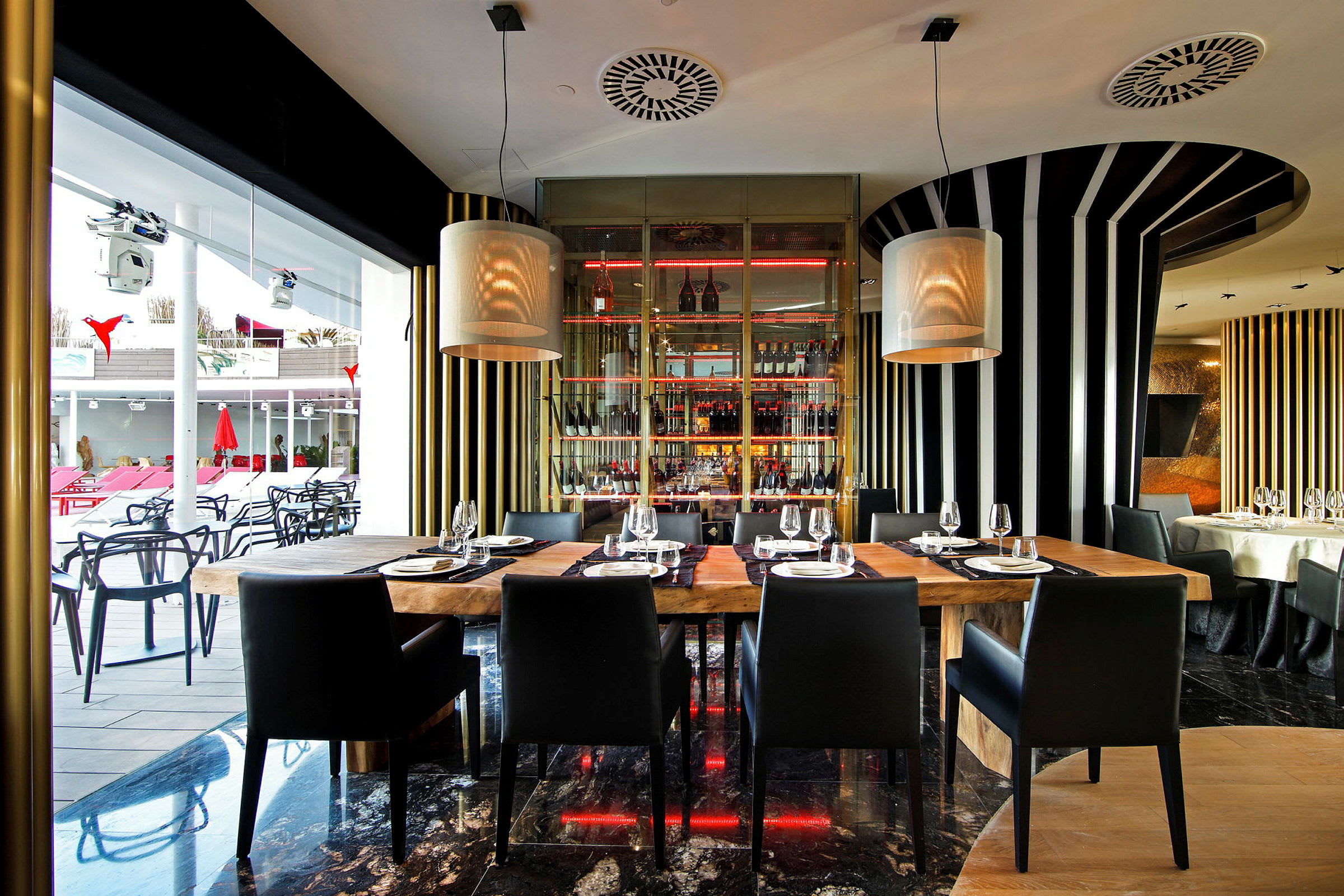Interiør av en moderne restaurant med trebord og svarte stoler, omgitt av stripete veggdekorasjoner og store vinduer. (AI-generert tekst)