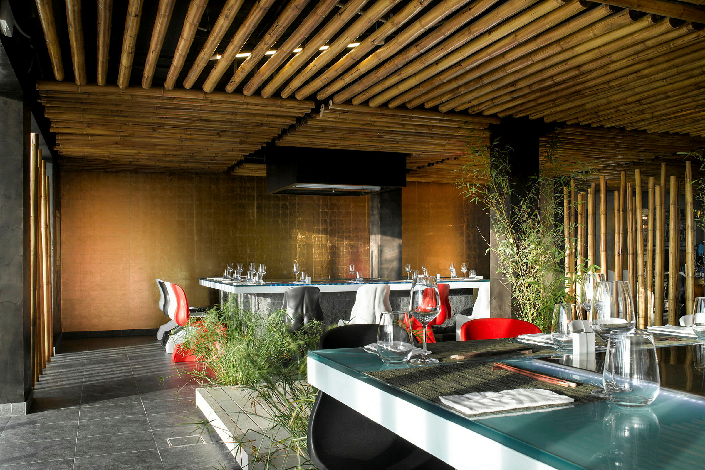 Interiør av en moderne restaurant med bambusinspirert tak, elegante møbler og grønne planter. (AI-generert tekst)