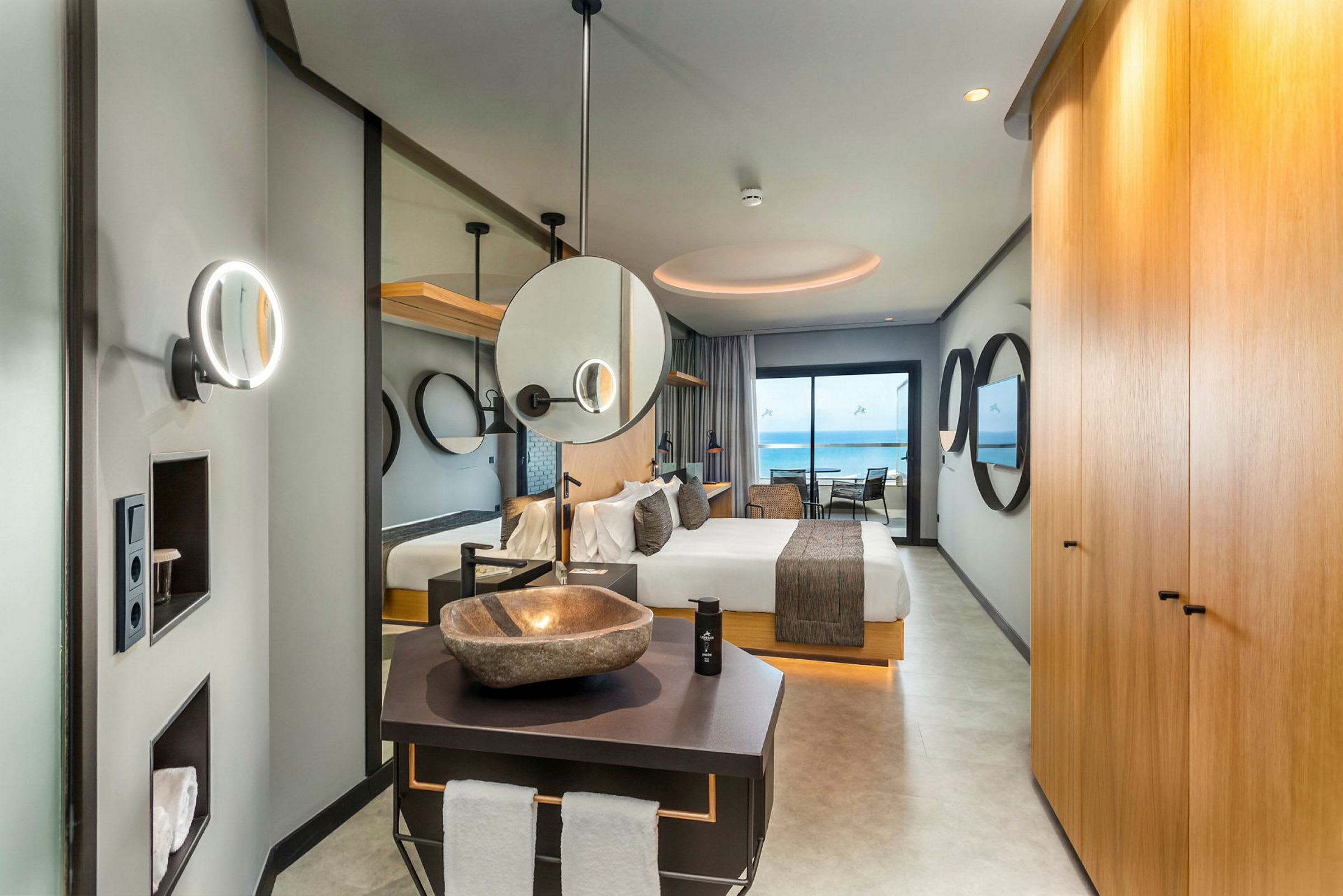 Interiør av et elegant hotellrom med seng, bad og utsikt mot havet. (AI-generert tekst)