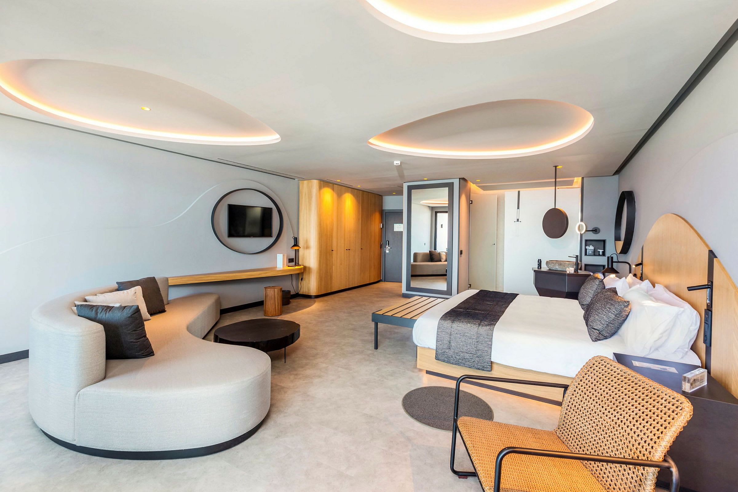 Et moderne hotellrom med en seng, en sofa og en stol med flettemønster. (AI-generert tekst)