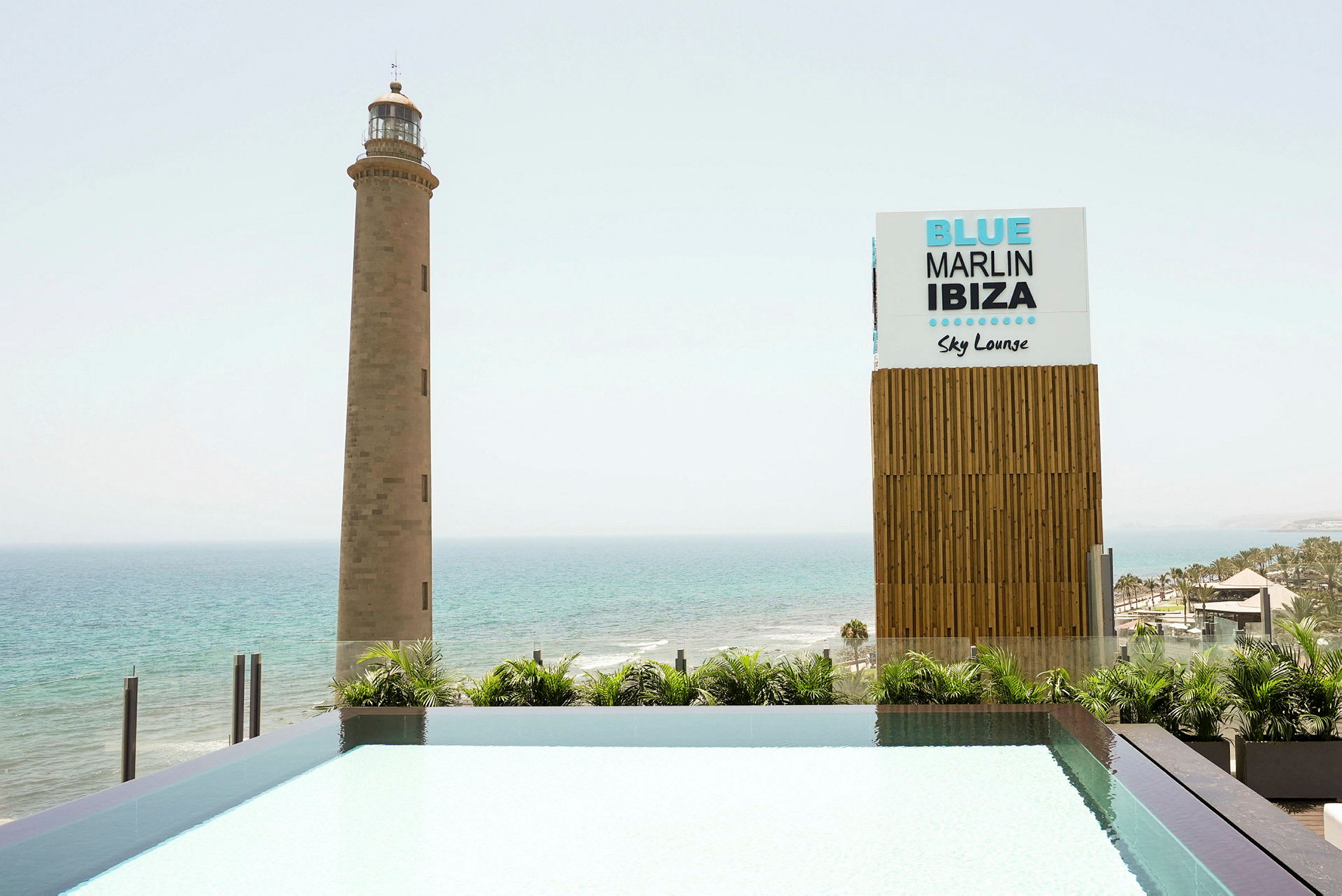 En fyr ved sjøen ved siden av et skilt som sier 'Blue Marlin Ibiza Sky Lounge'. (AI-generert tekst)