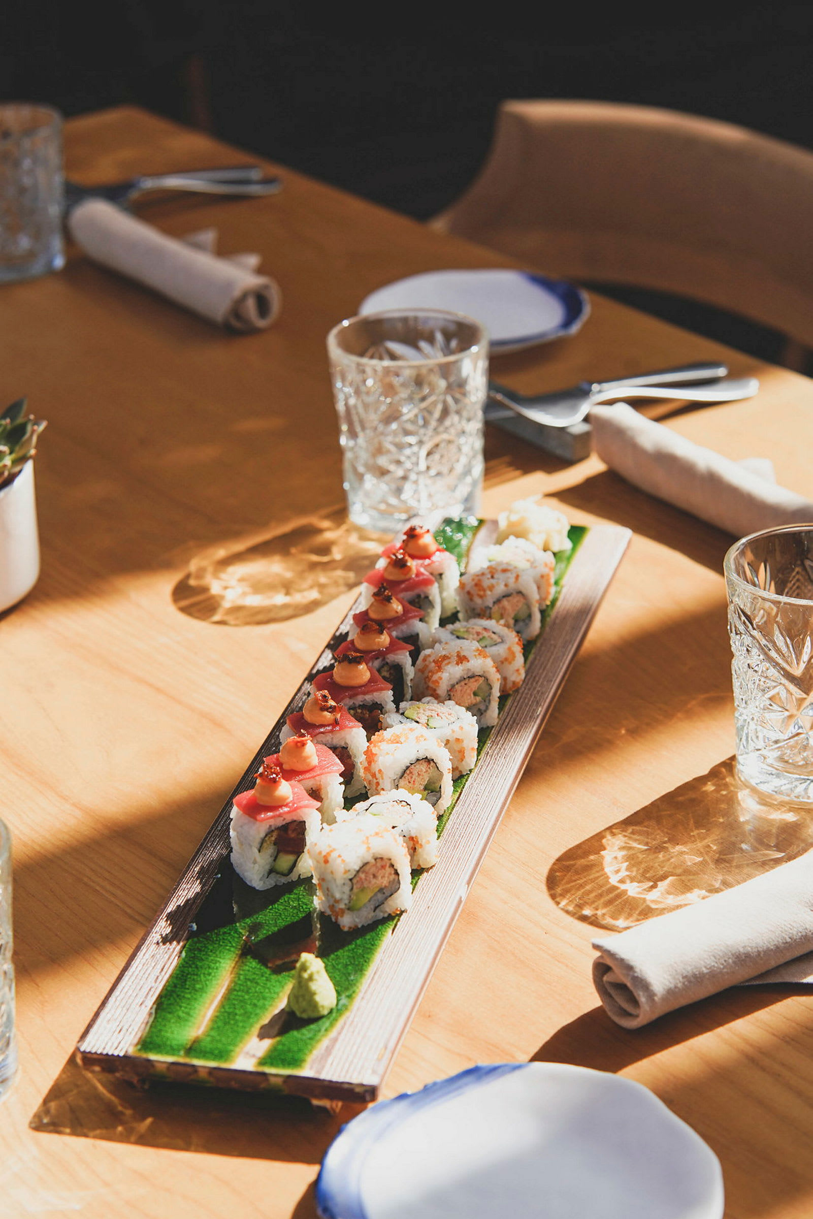 Sushi servert på et avlangt fat på et bord dekket til måltid. (AI-generert tekst)
