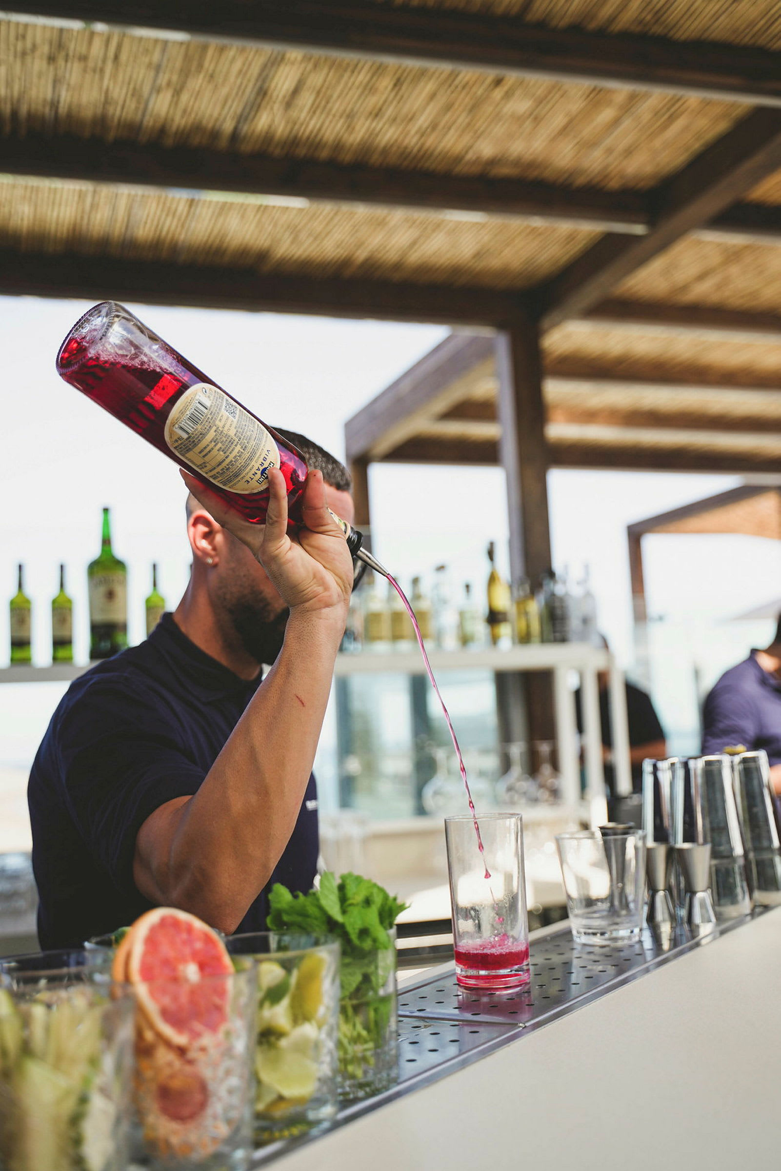 Bilde av en bartender som heller rosa væske i et glass. (AI-generert tekst)