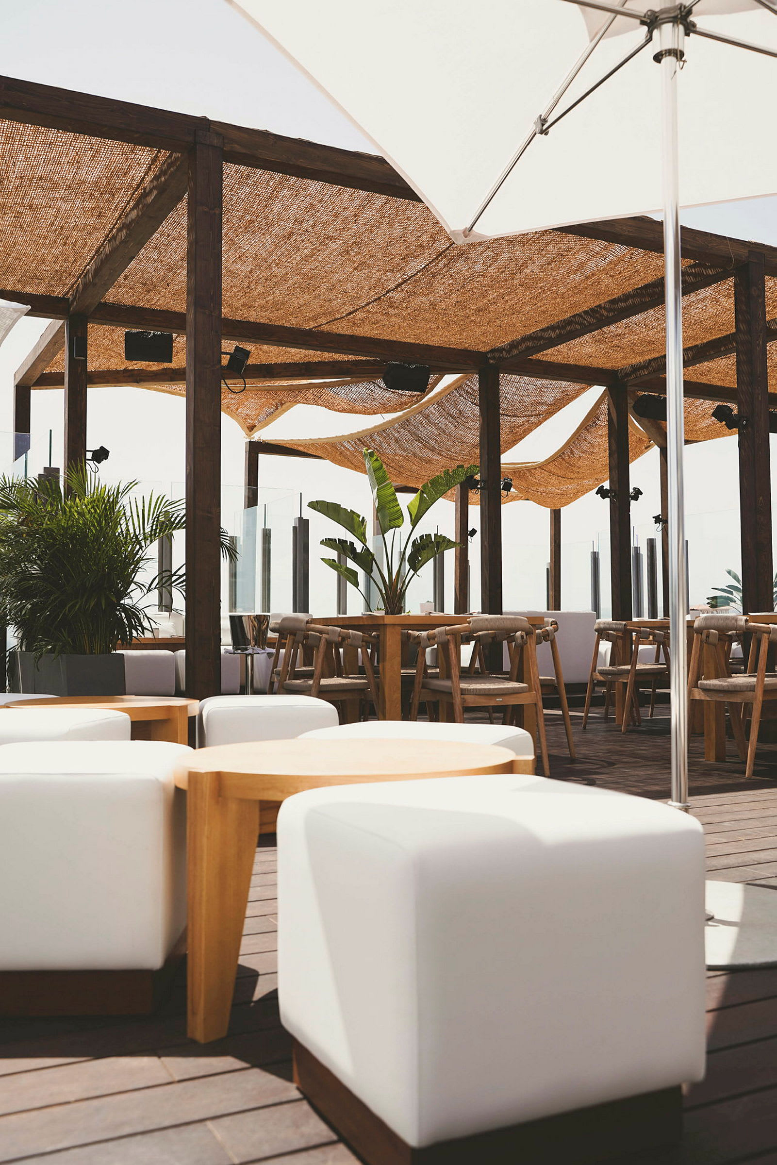 Utendørs terrasse med sittemøbler, planter og skyggefulle baldakiner. (AI-generert tekst)