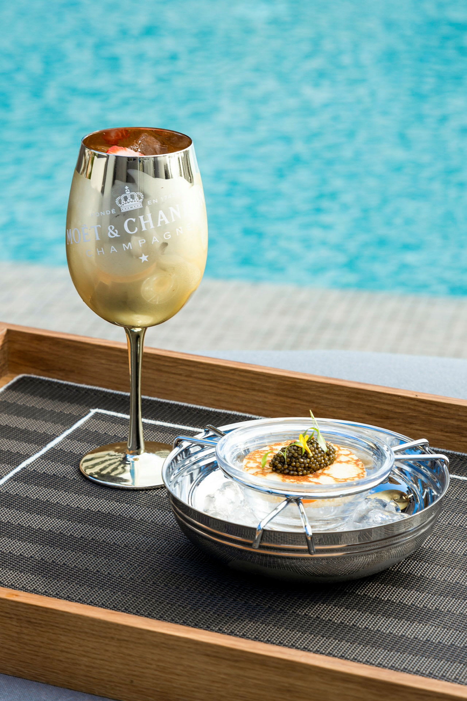 Gullfarget champagneglass ved siden av en servering med kaviar på is. (AI-generert tekst)