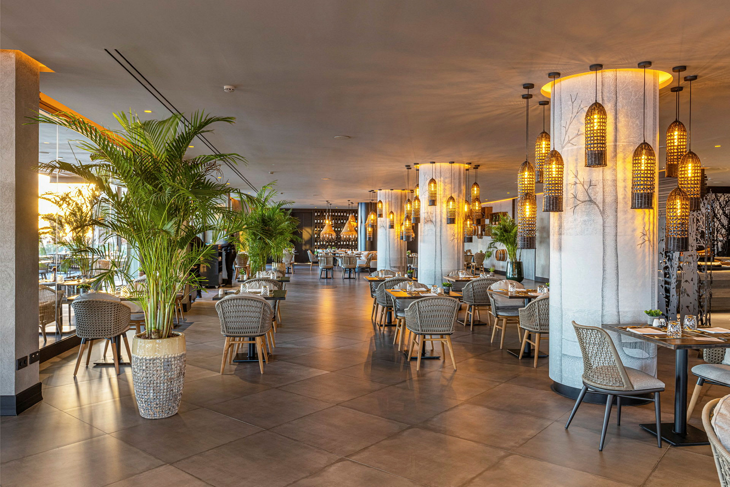 En moderne restaurant med bord og stoler, omgitt av dekorasjoner og planter. (AI-generert tekst)