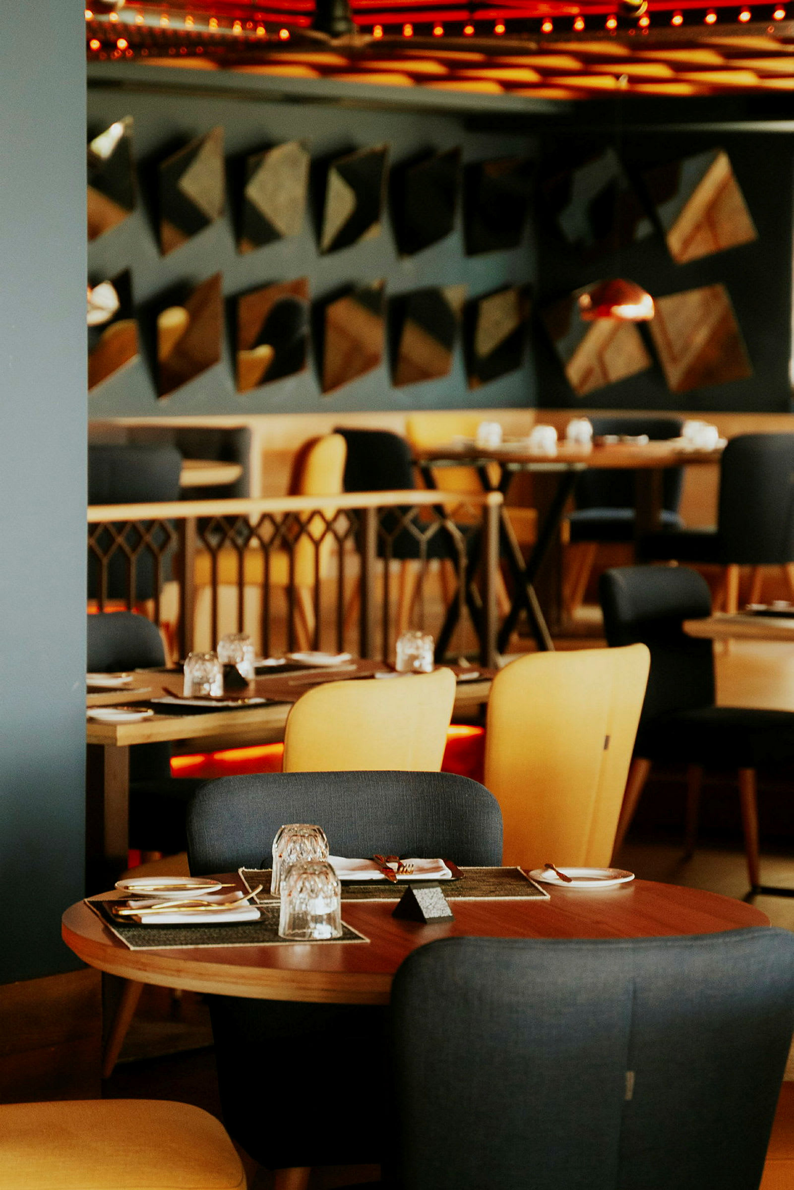 En restaurantinnstilling med bord og stoler, dekket for måltider. (AI-generert tekst)