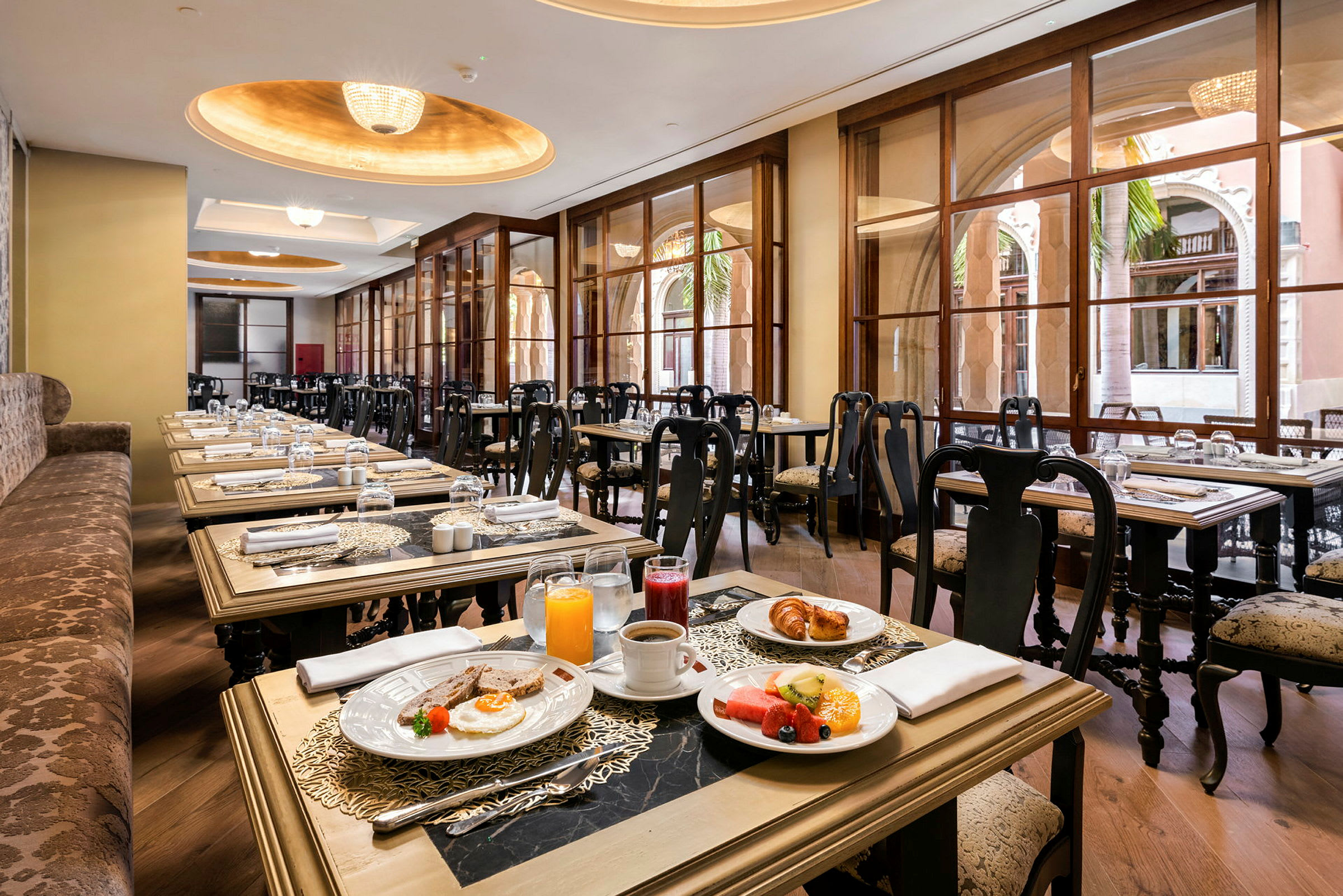 Bilde av en restaurant med elegante sitteplasser og vinduer samt bord dekket med frokost. (AI-generert tekst)
