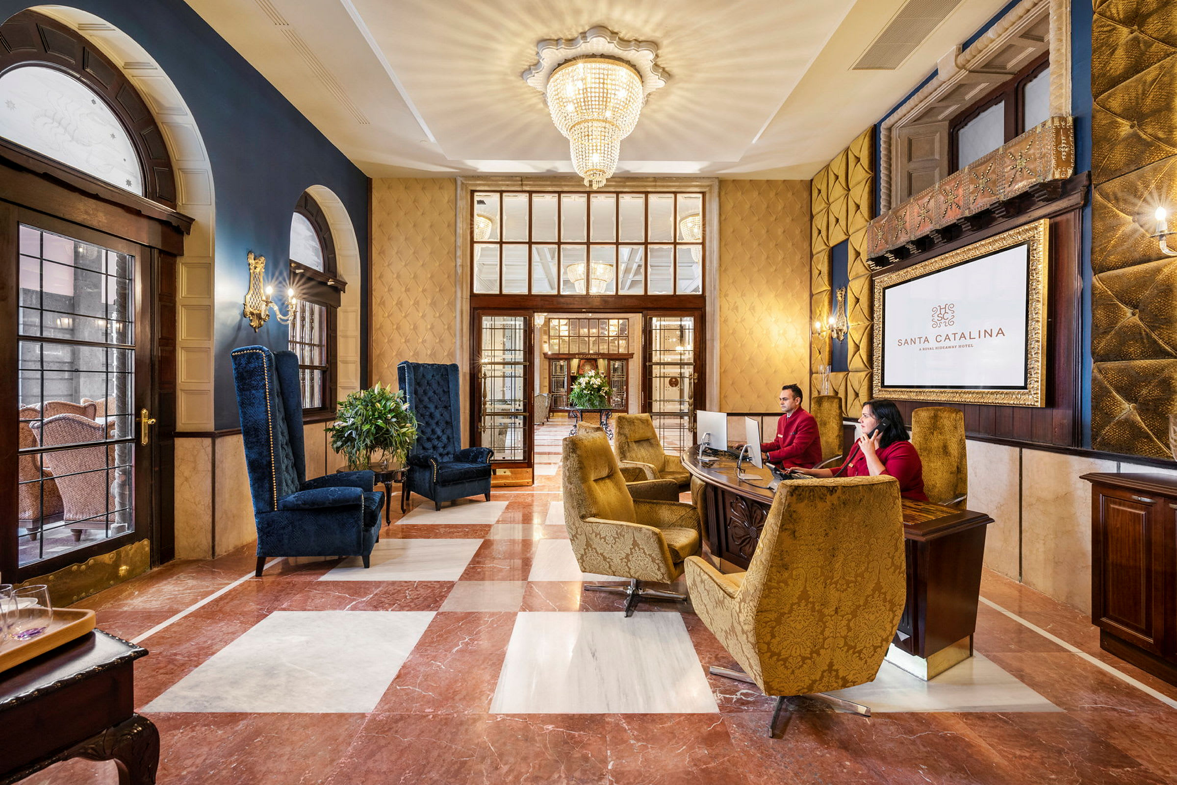 Hotellobby med elegante sittegrupper og resepsjon. En stor krystalllysekrone henger i taket. (AI-generert tekst)