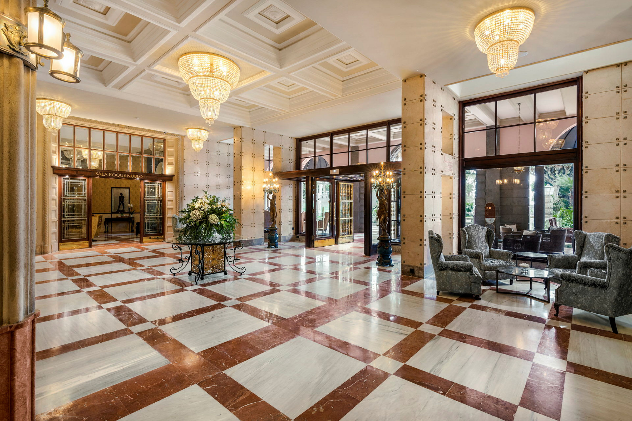 Elegant hotellobby med marmorgulv, store lysekroner og sittemøbler. (AI-generert tekst)
