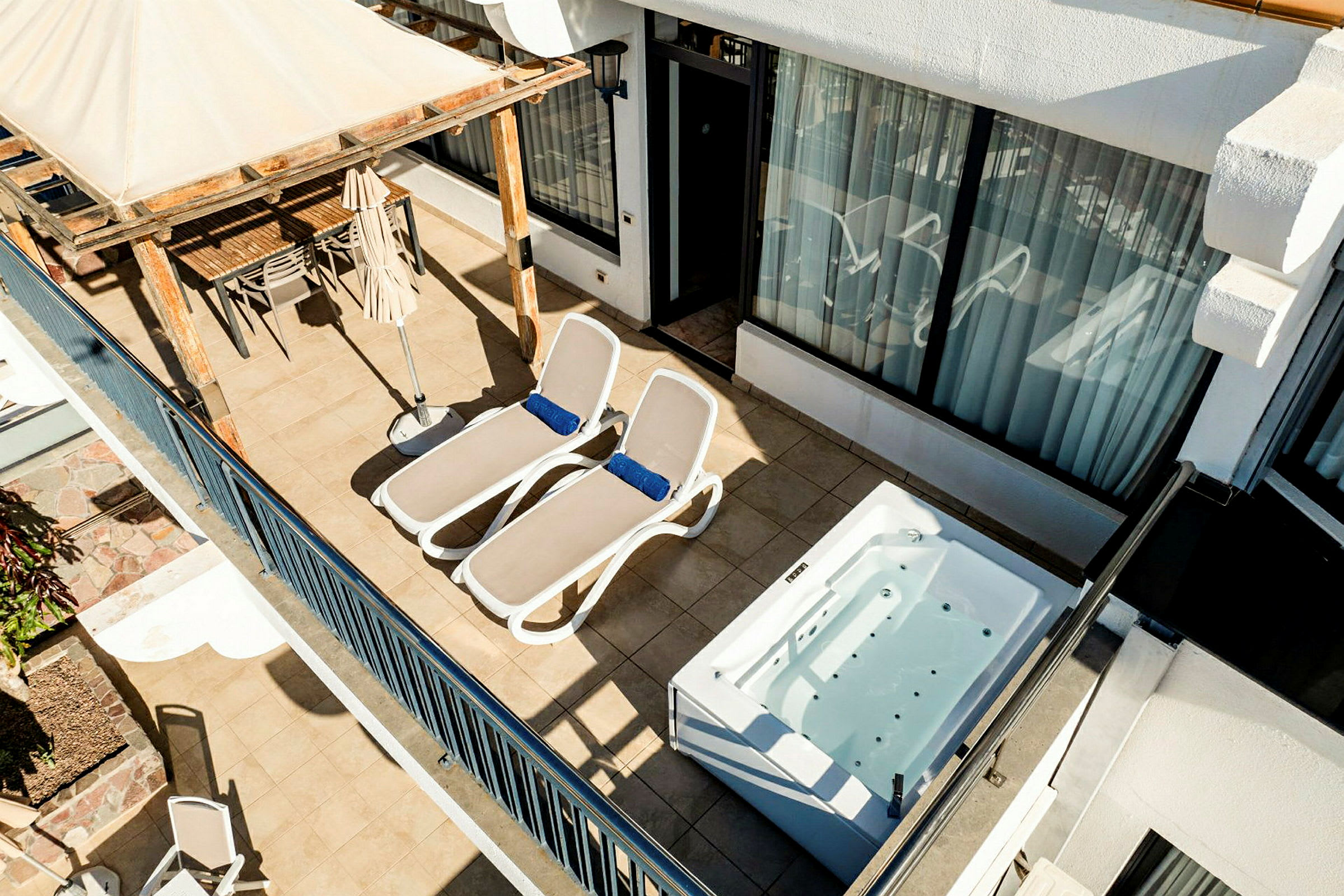 En terrasse med to solsenger, et boblebad og en spiseplass under en pergola. (AI-generert tekst)