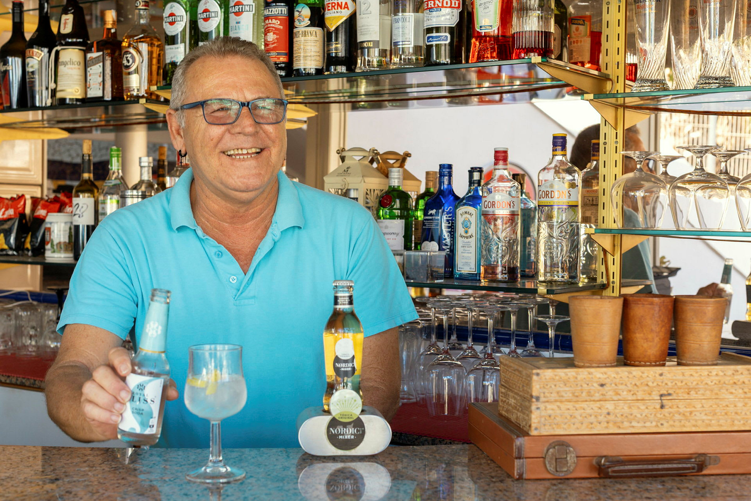 En bar med forskjellige spritflasker på hyller og et serveringsbord med drikkevarer. (AI-generert tekst)