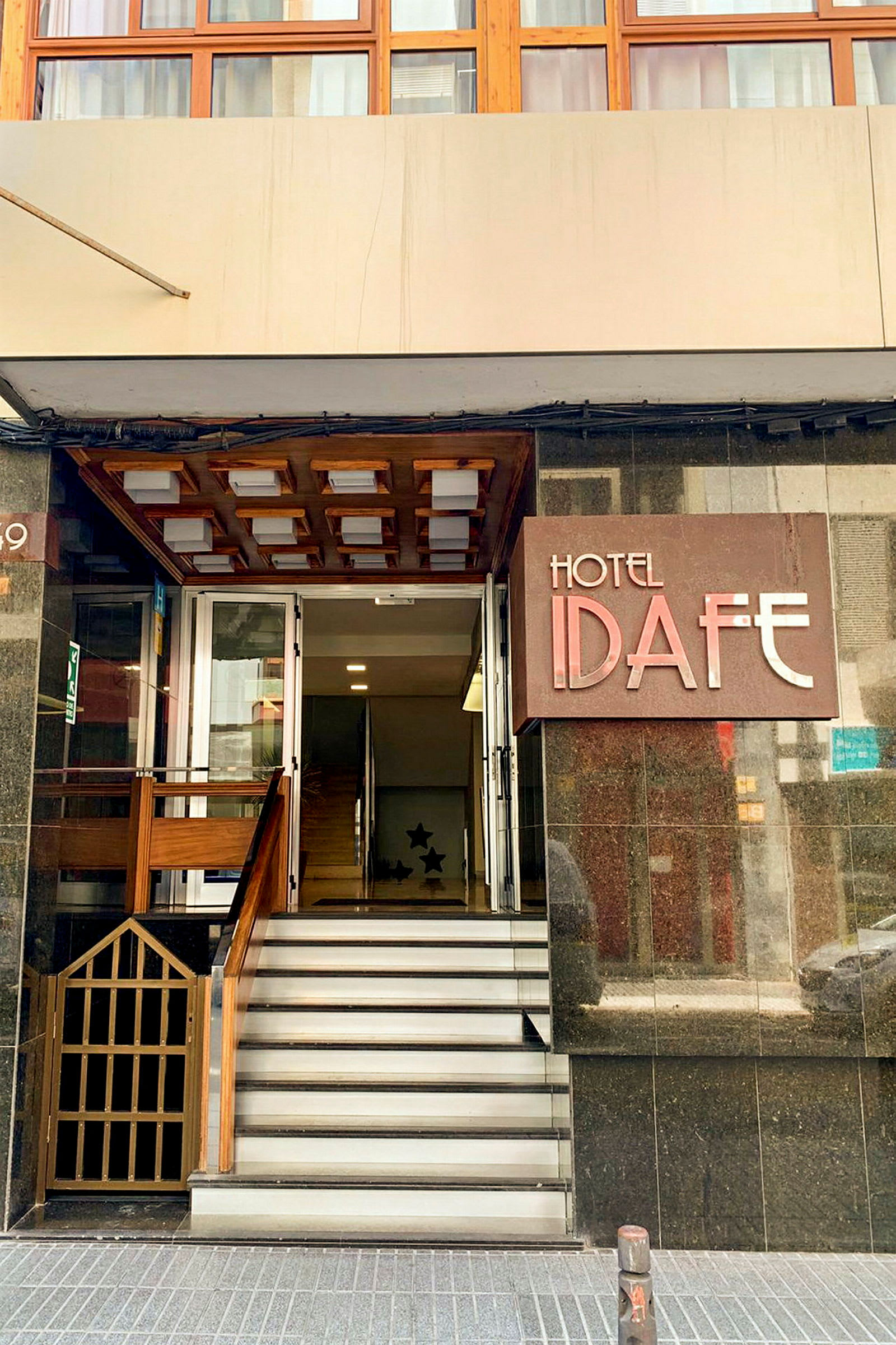 Inngangen til Hotel Idafe med noen trappetrinn og en dør. (AI-generert tekst)