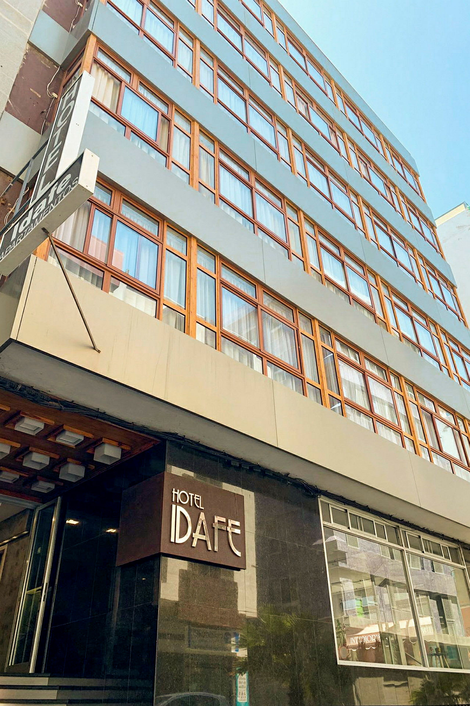 En bygning med flere etasjer og skilt med teksten 'Hotel Idafe' ved inngangen. (AI-generert tekst)