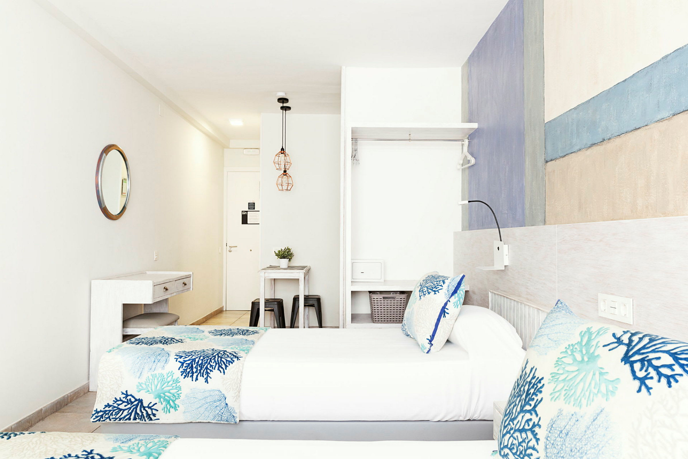To enkeltsenger med blåmønstret sengetøy i et lyst og moderne hotellrom. (AI-generert tekst)