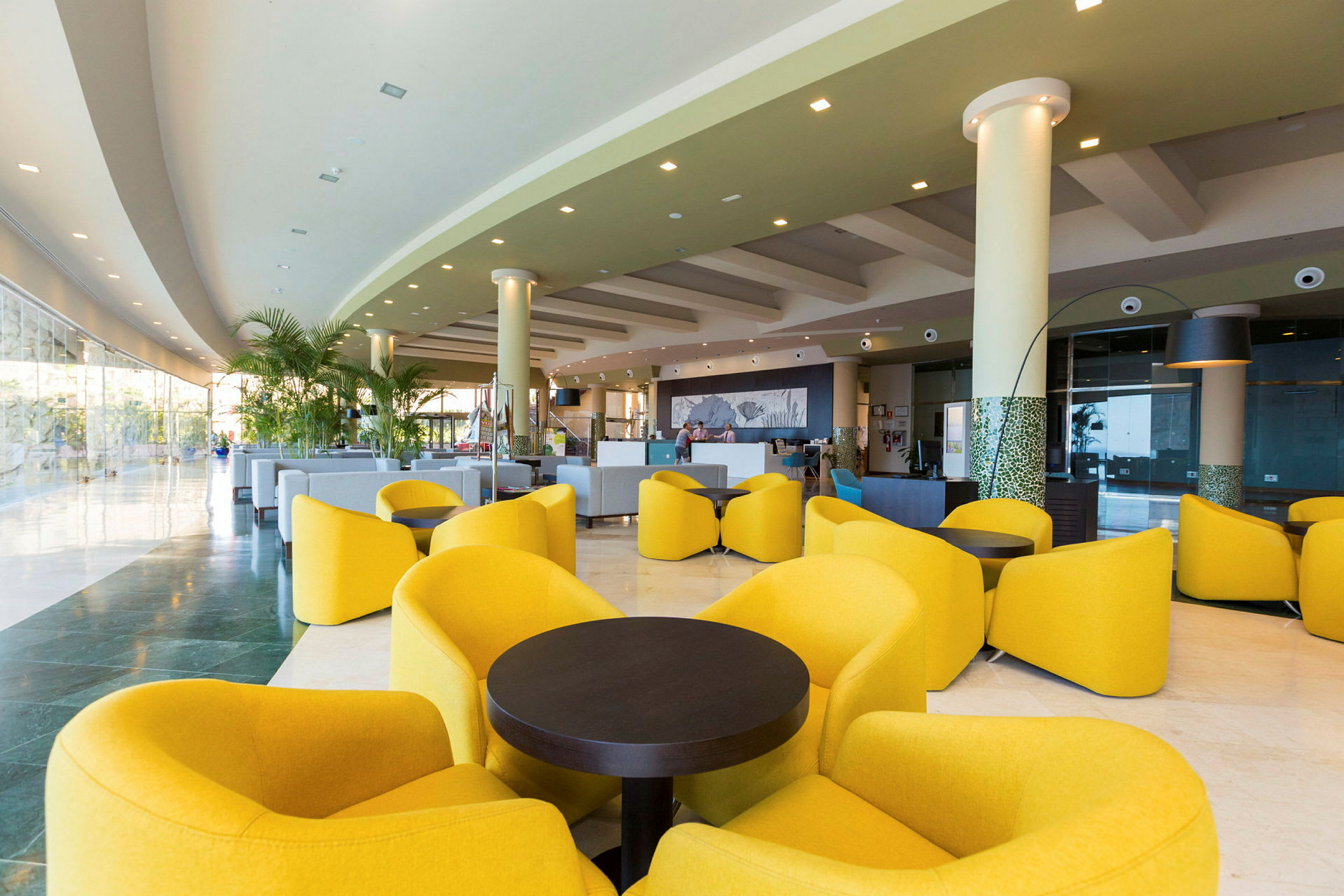 Interiør av en moderne hotellobby med gule loungestoler og sofaer. (AI-generert tekst)