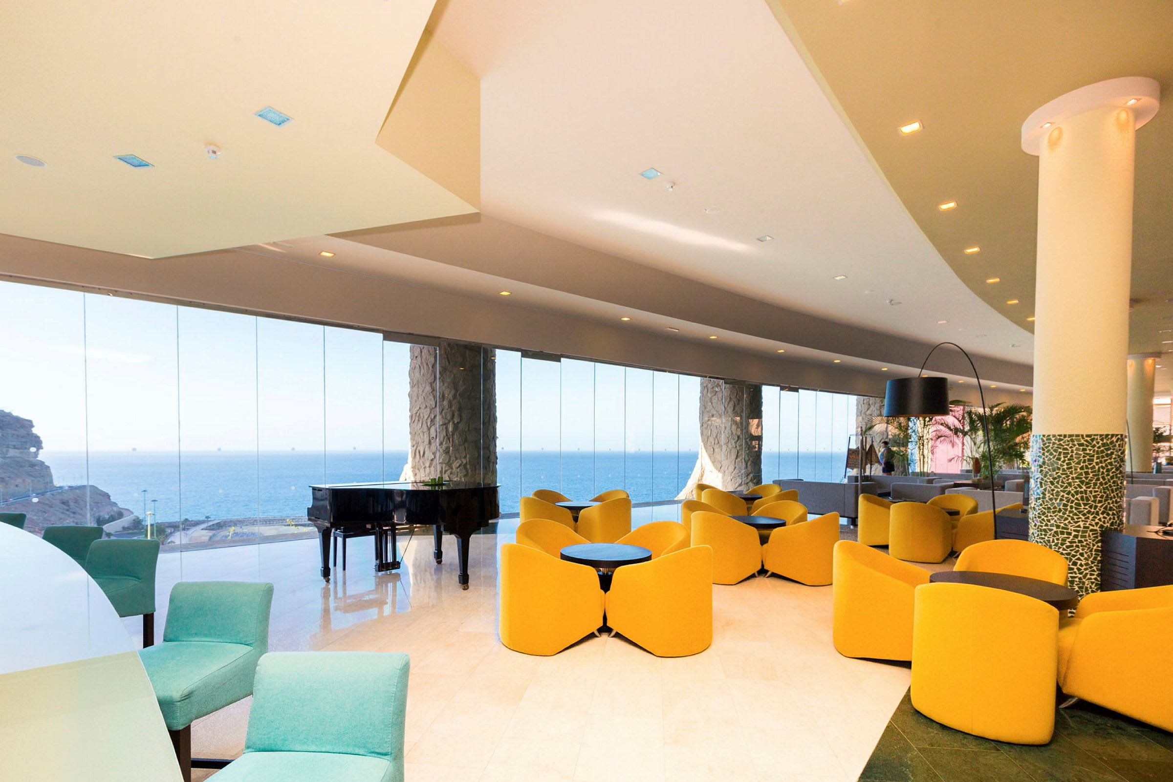 En hotellobby med moderne møbler, store glassvegger og utsikt over havet. (AI-generert tekst)