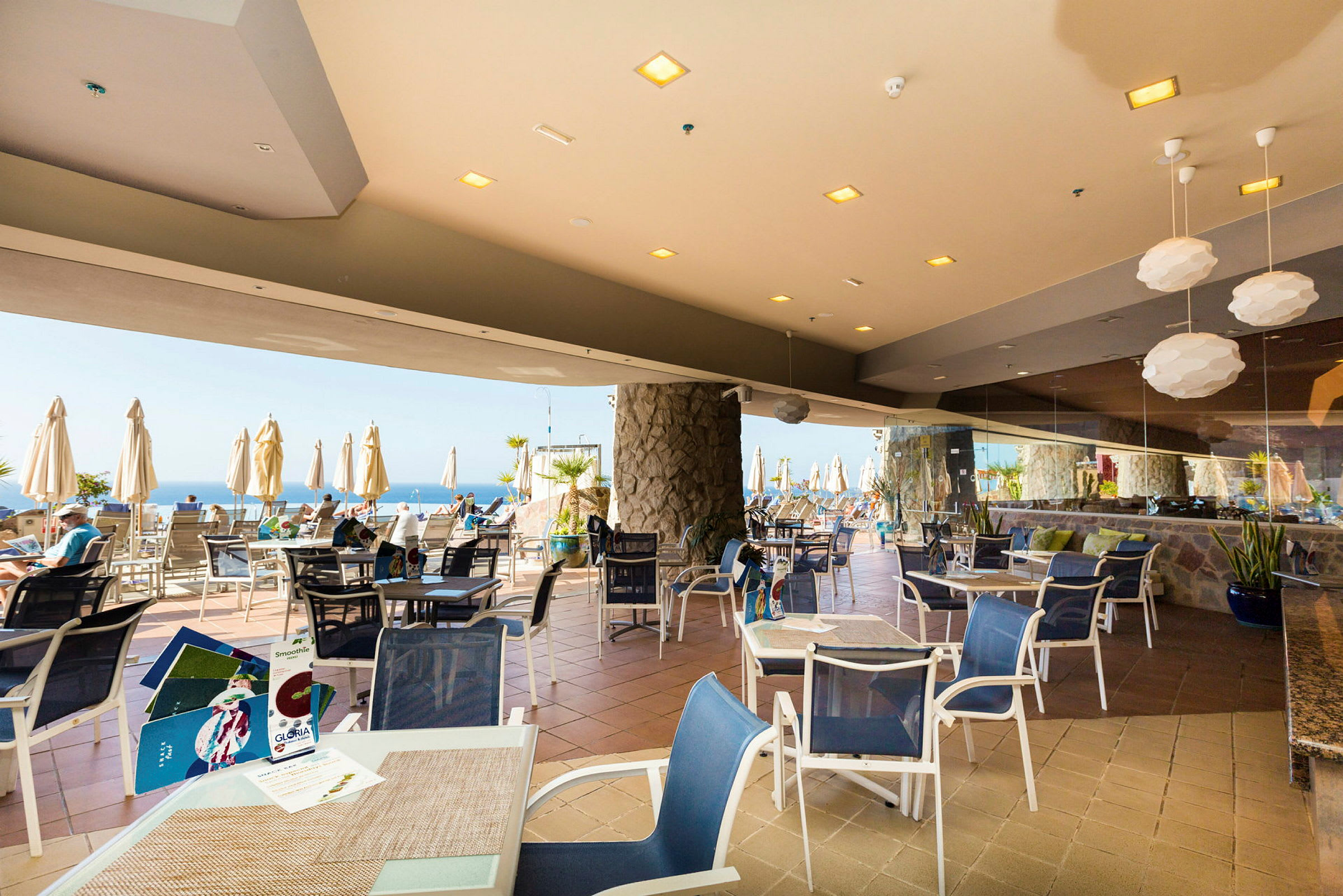 Restaurant taverna med bord og stoler samt utsikt mot havet. (AI-generert tekst)