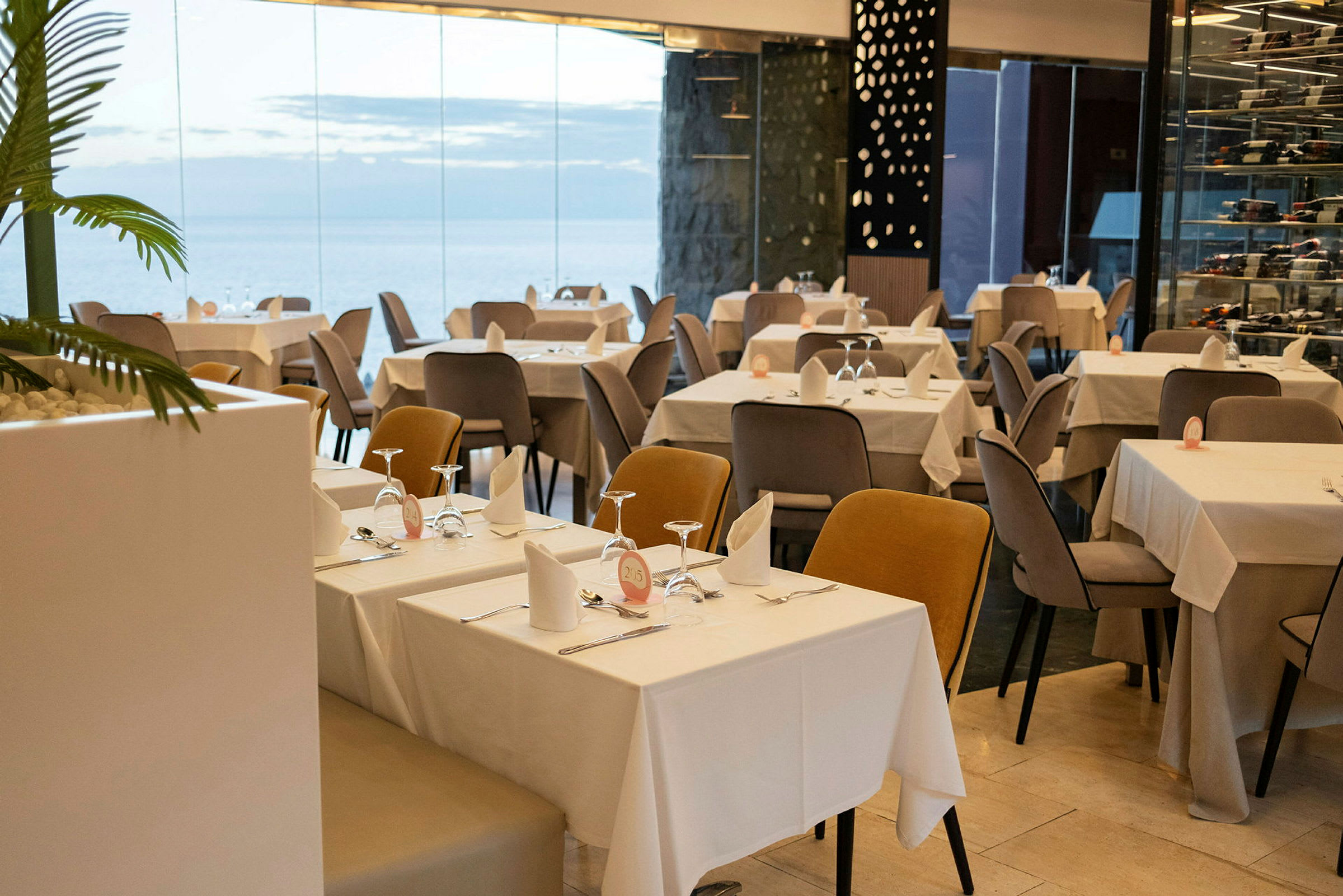 Restaurant med dekkede bord og stoler i et moderne miljø med glassvegger. (AI-generert tekst)
