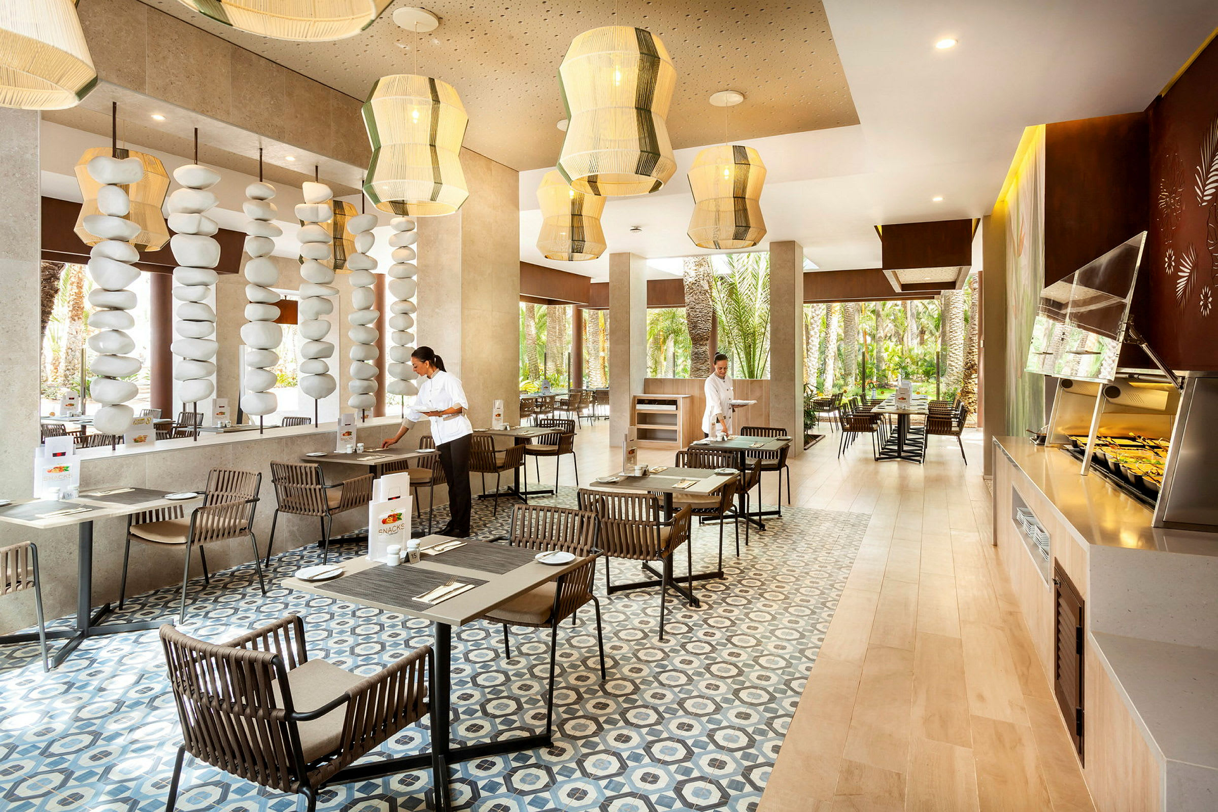 En moderne restaurant med store vinduer, trebord og komfortable stoler, samt dekorative taklamper og steinformasjoner. (AI-generert tekst)