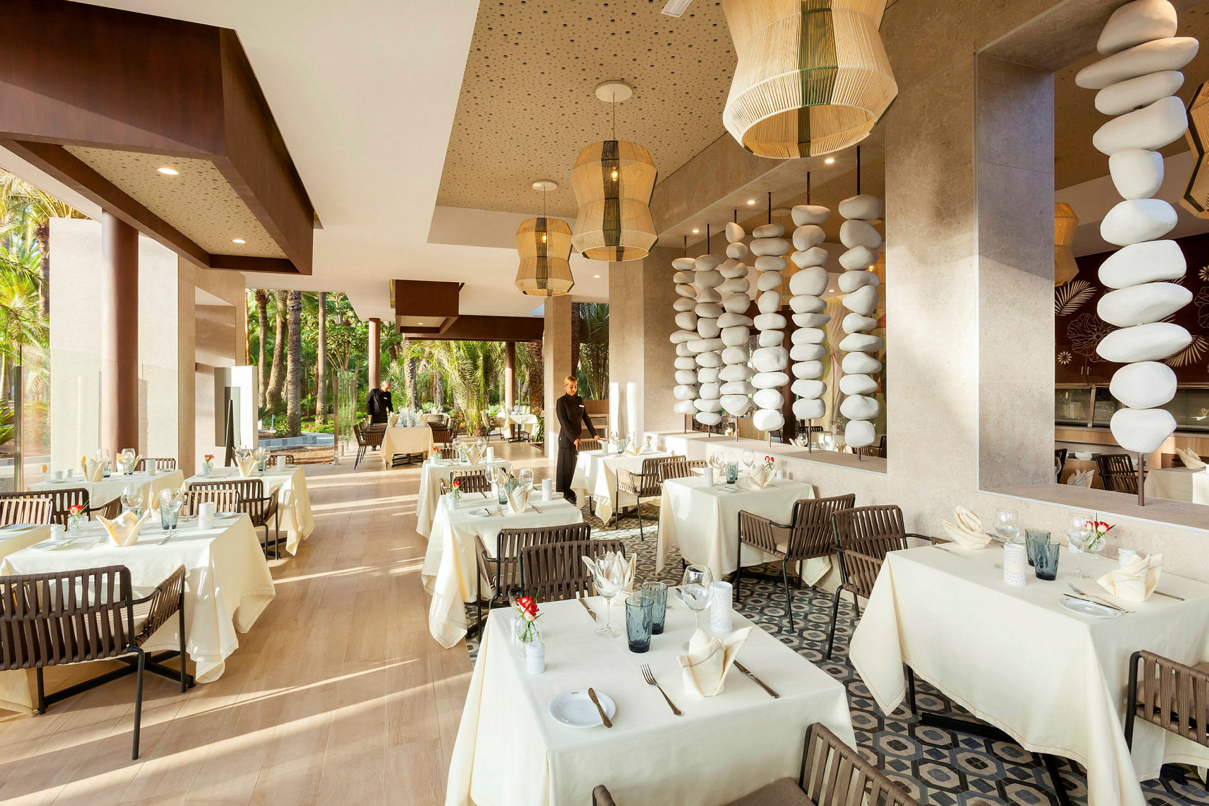 En elegant restaurant med hvite duker, dekorerte bord og store vinduer mot grønt. (AI-generert tekst)