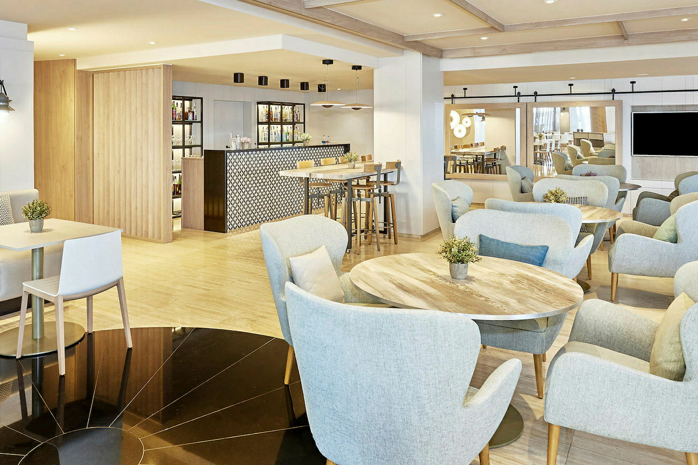 Interiør av en moderne kafé med lyse møbler og en bardisk. (AI-generert tekst)