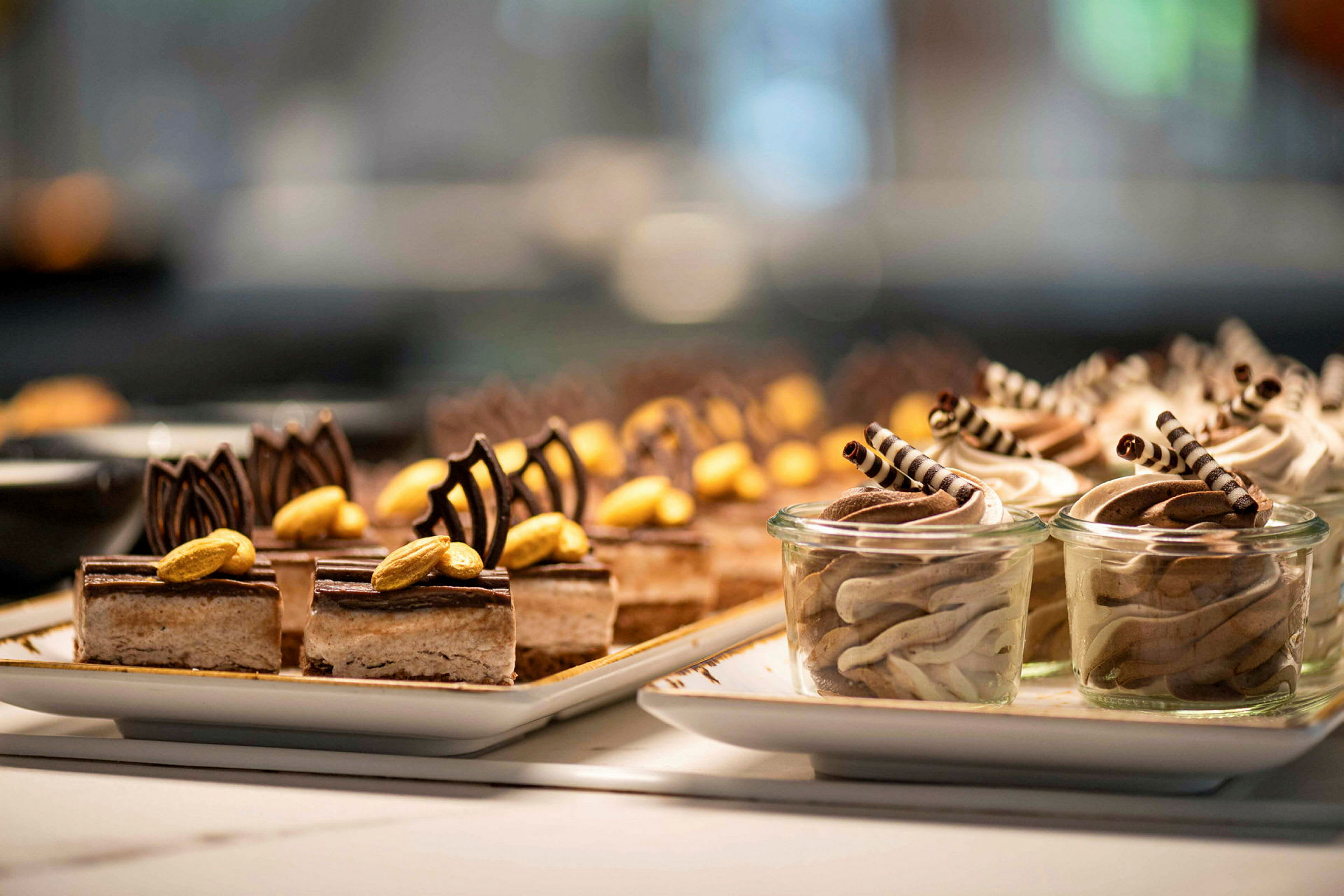 Tallerkener med små desserter dekorert med sjokolade og nøtter. (AI-generert tekst)