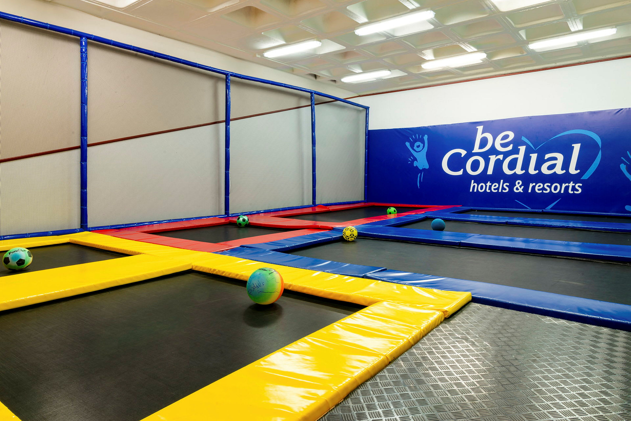 En innendørs trampolinepark med fargerike trampoliner og baller. (AI-generert tekst)