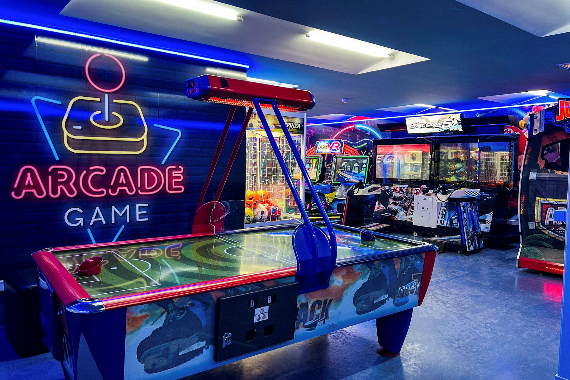 Neonbelyst arkadespillrom med air hockey-bord og spilleautomater. (AI-generert tekst)