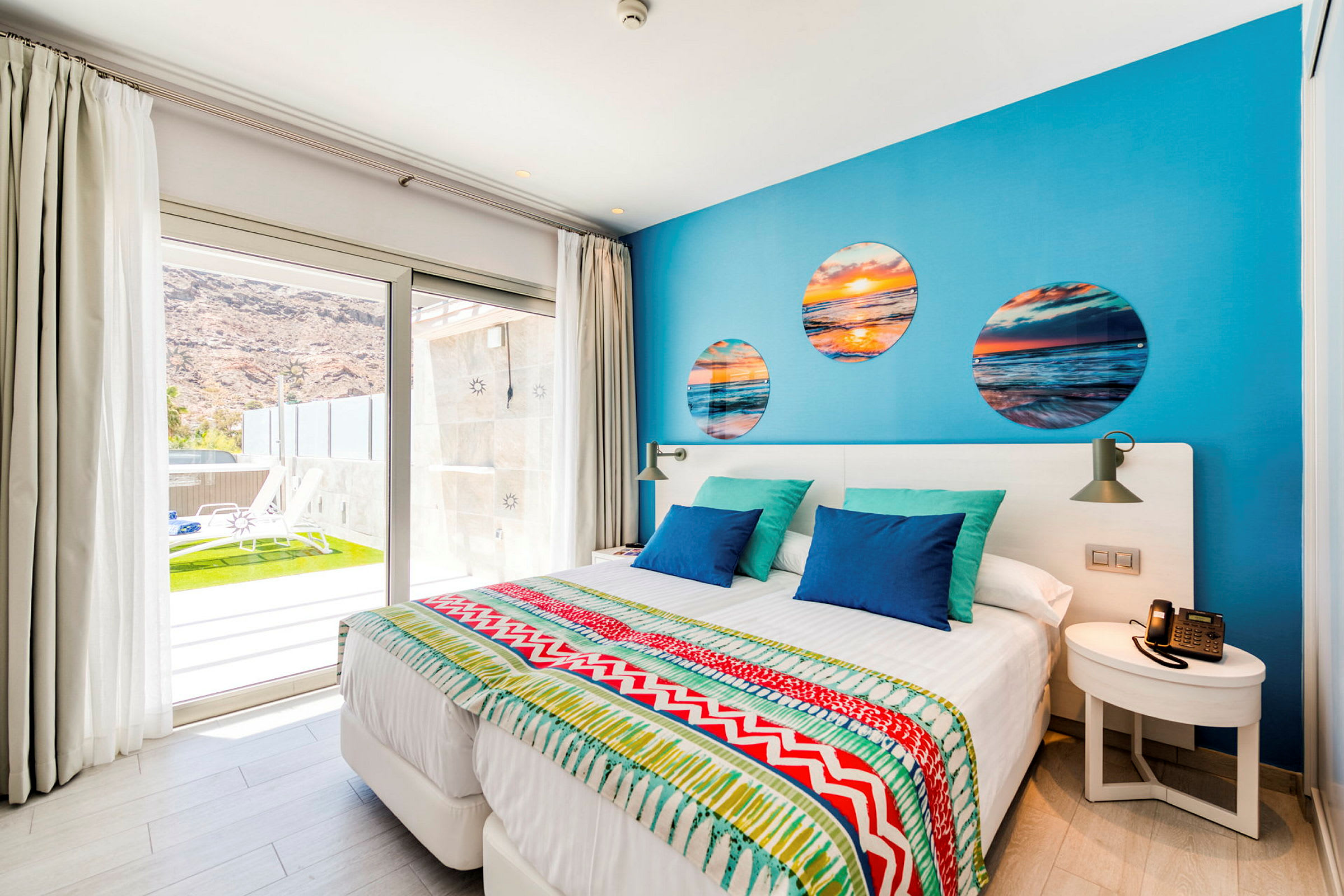Moderne hotellrom med fargerik innredning og utsikt over terrasse. (AI-generert tekst)