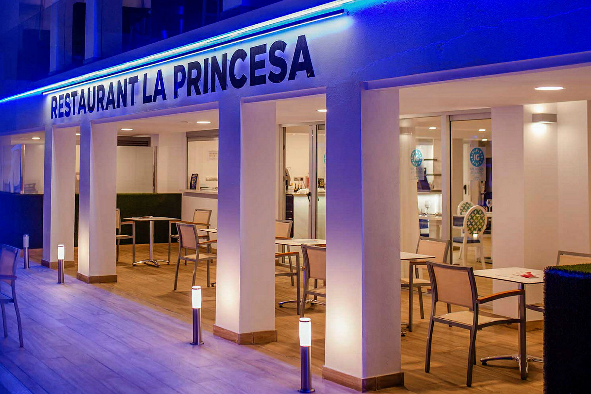Restaurant La Princesa med bord og stoler på en opplyst terrasse. (AI-generert tekst)