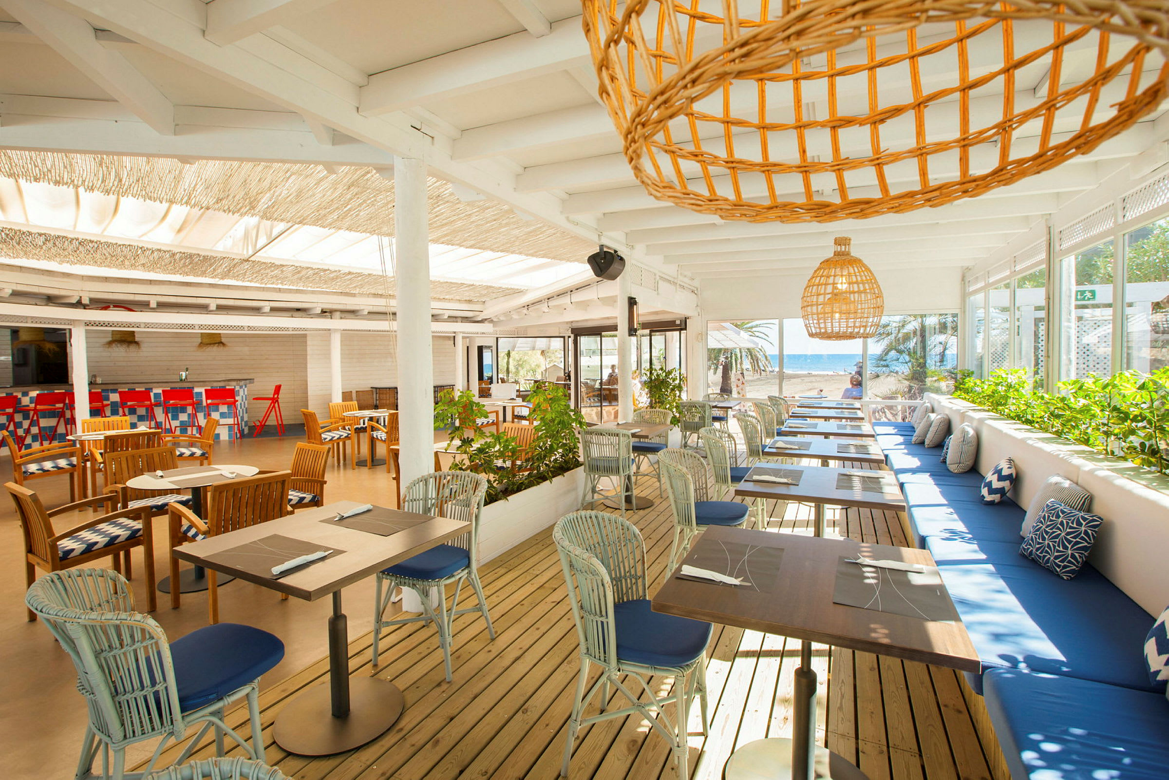 En åpen restaurant med bord og stoler og utsikt mot havet. (AI-generert tekst)