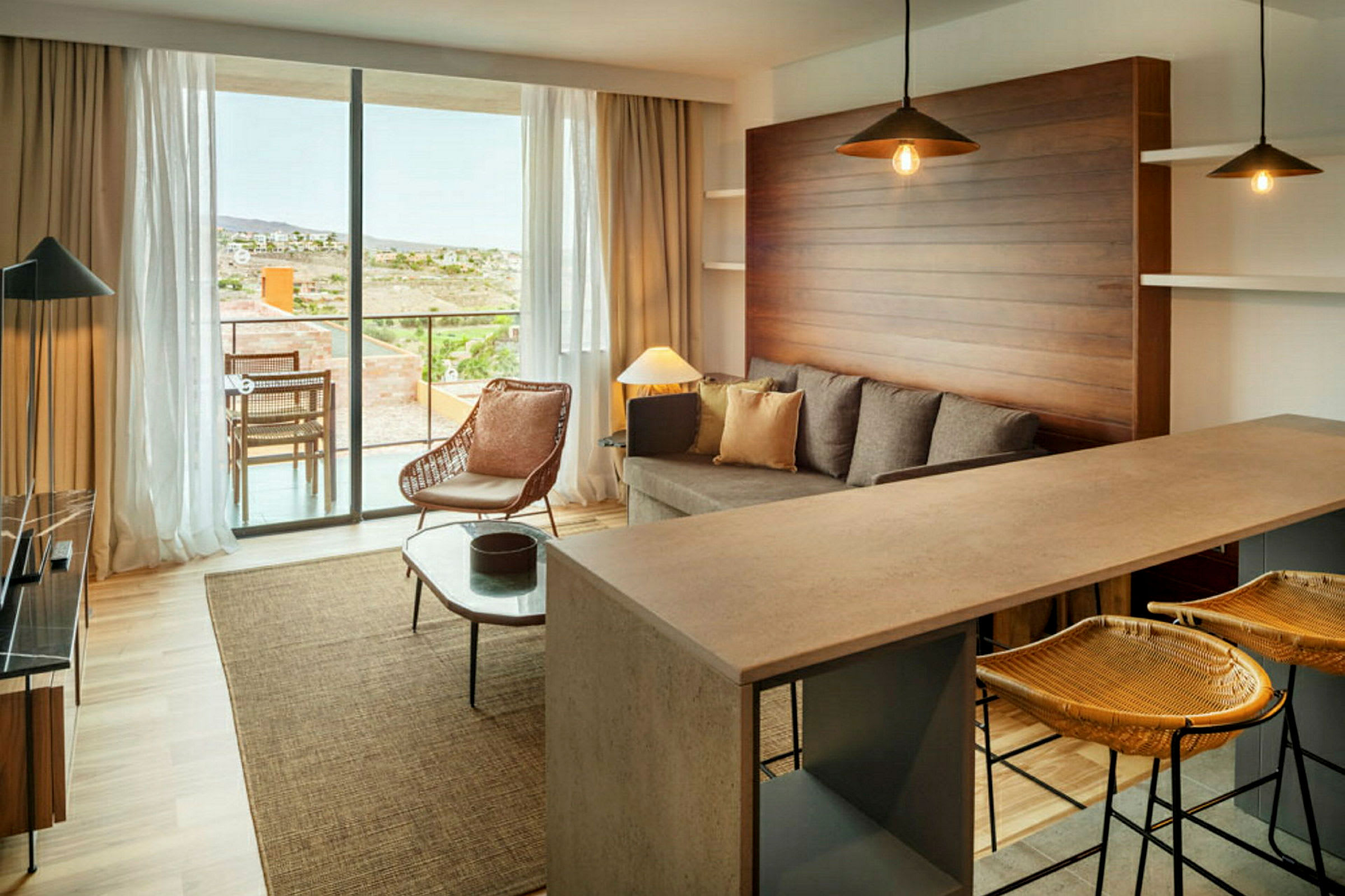 En moderne stue med sofa, lenestol og kjøkkenbar. Store vinduer vender mot en terrasse. (AI-generert tekst)