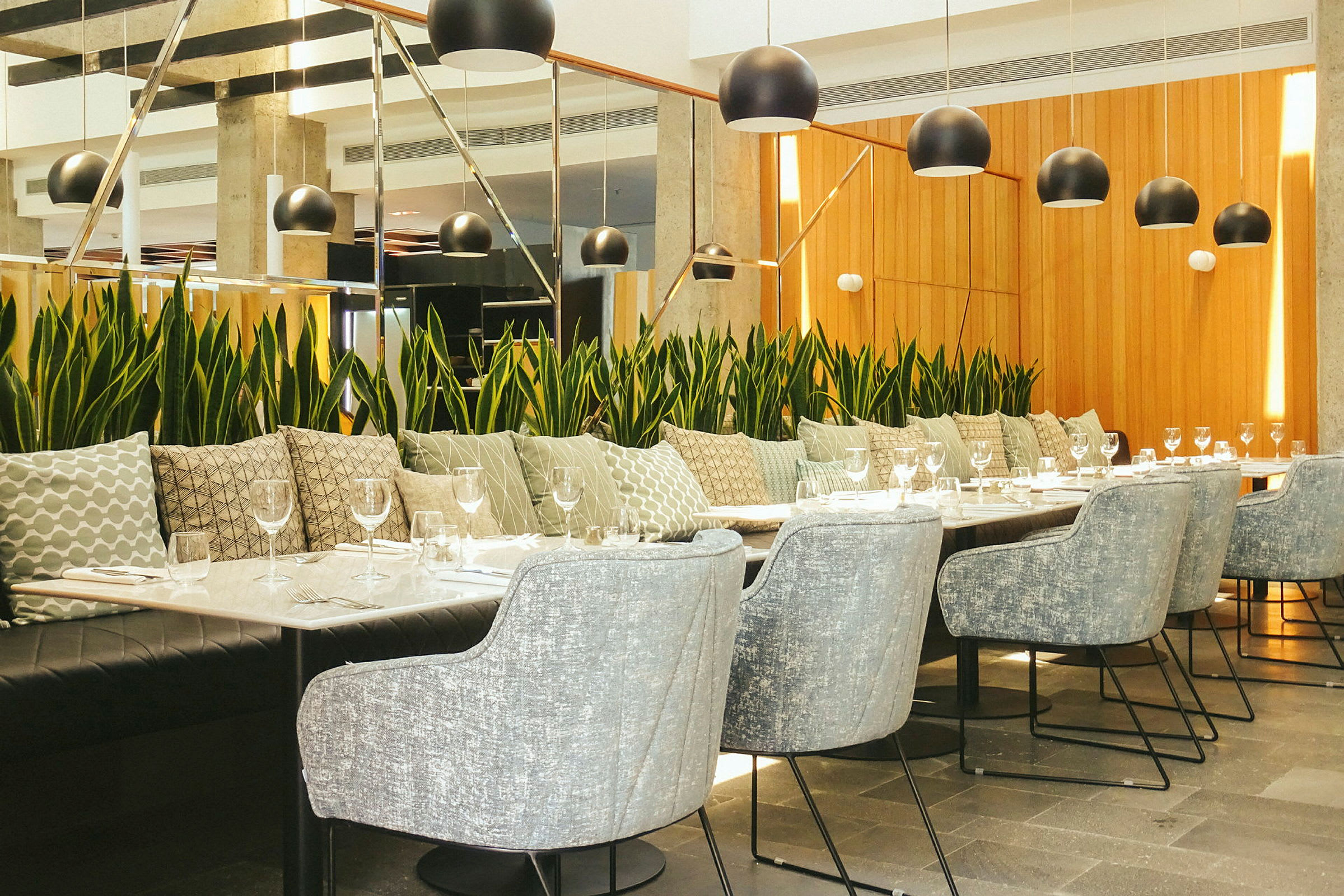 Moderne restaurantinteriør med et langbord omgitt av stoler og plantepynt. (AI-generert tekst)