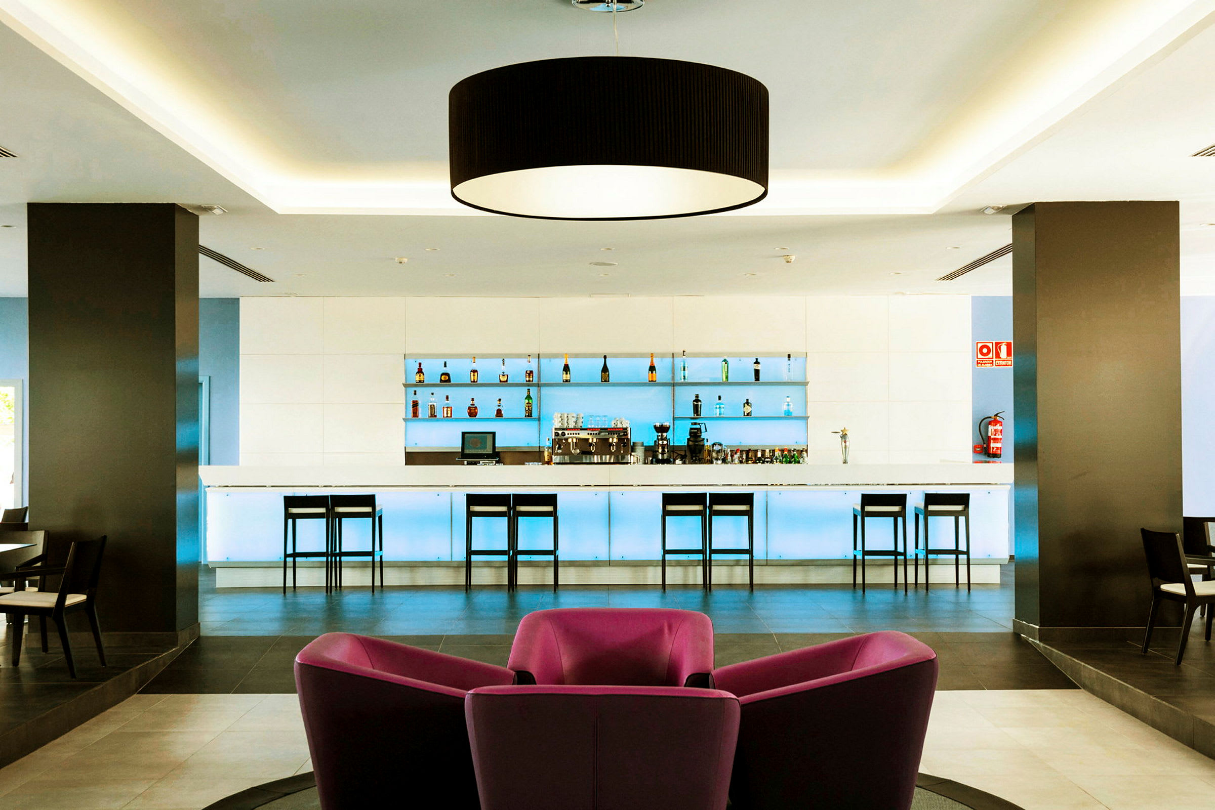 Moderne hotellbar med stoler og flaskedisplay. (AI-generert tekst)