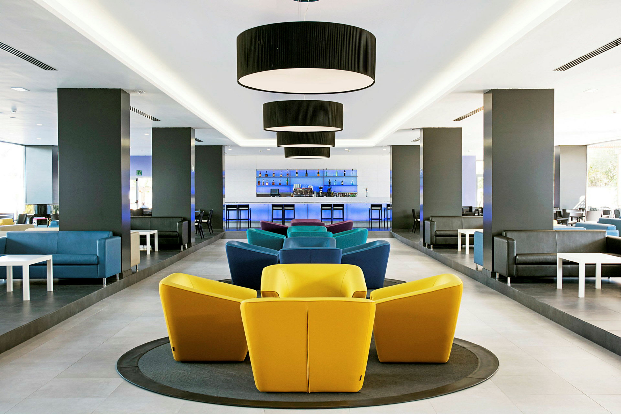 Moderne lounge med fargerike stoler og bar i bakgrunnen. (AI-generert tekst)