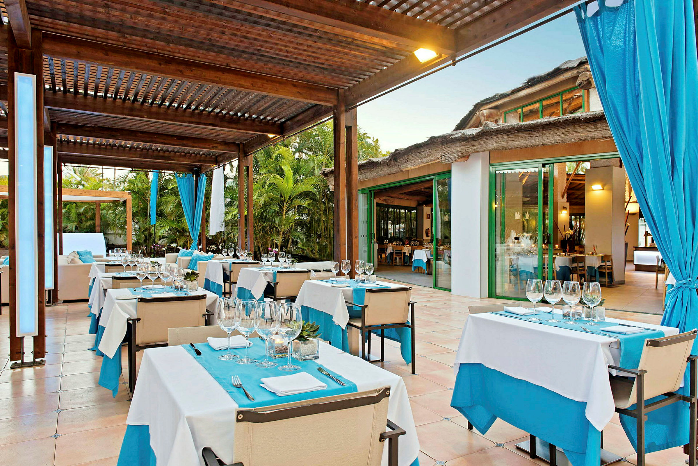 En utendørsrestaurant med dekkede bord under en trepergola. (AI-generert tekst)