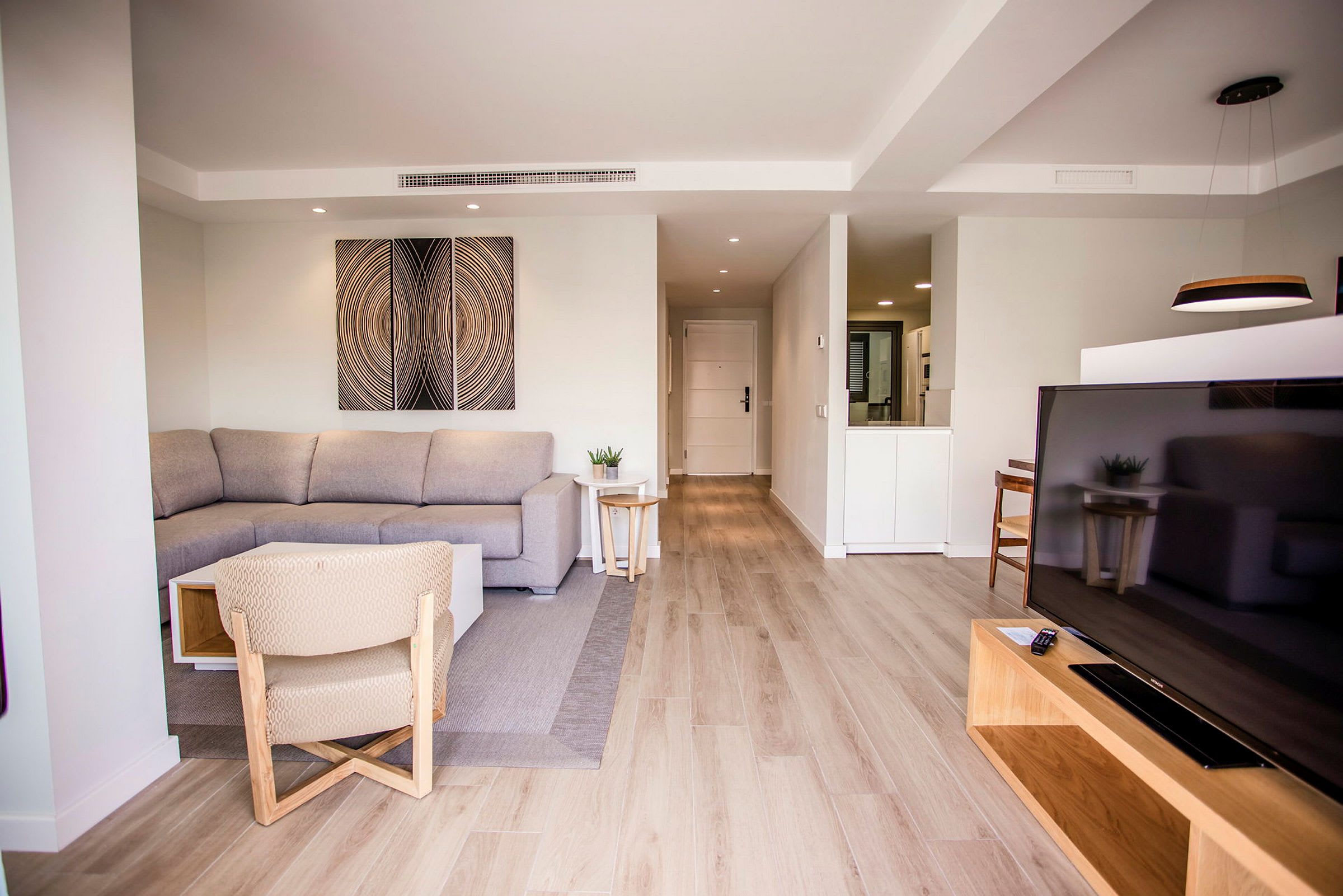 En moderne stueinnredning med sofa, TV og lyse tredetaljer. (AI-generert tekst)