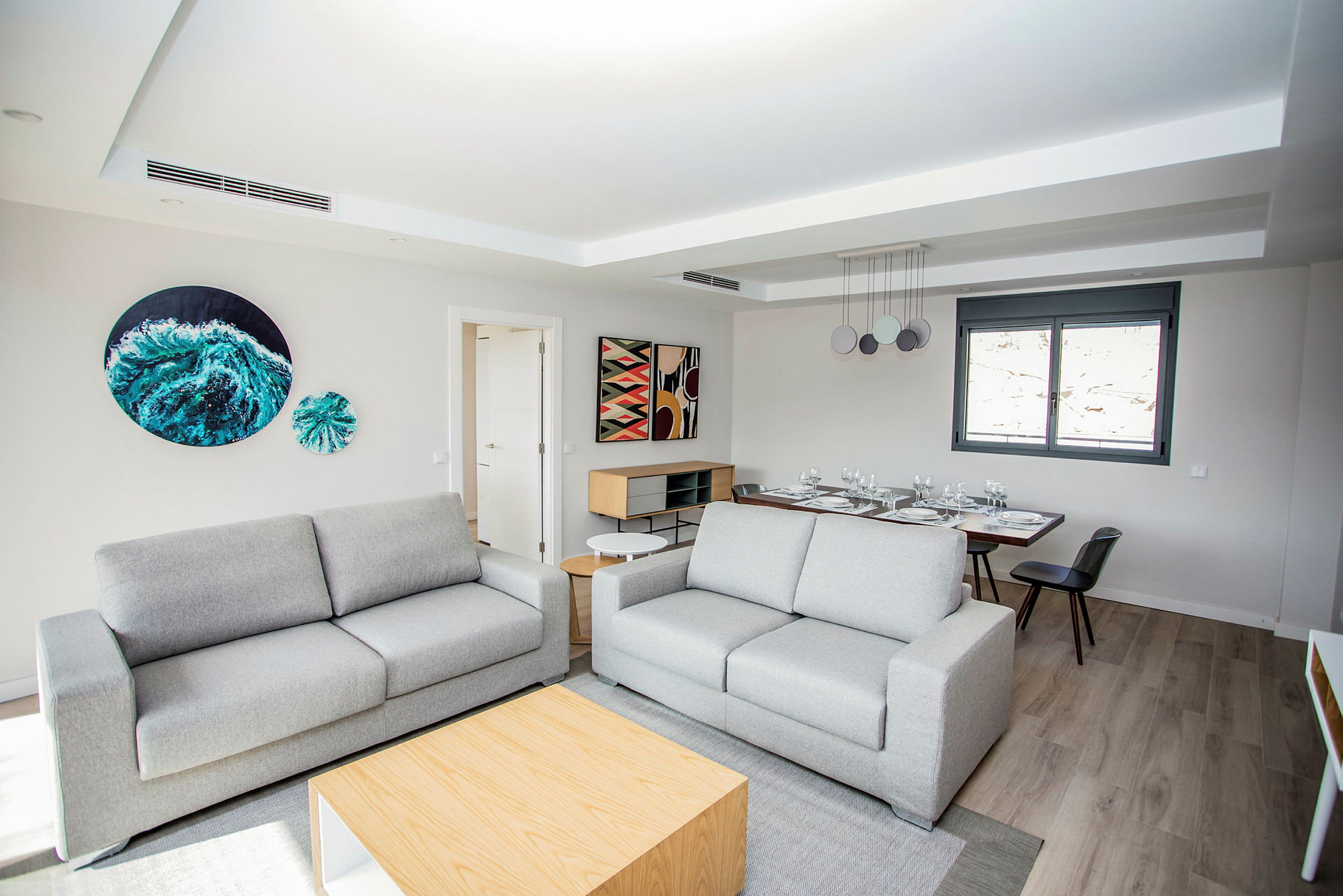 En moderne innredet sitteplass med to sofaer og et spisebord i bakgrunnen. (AI-generert tekst)