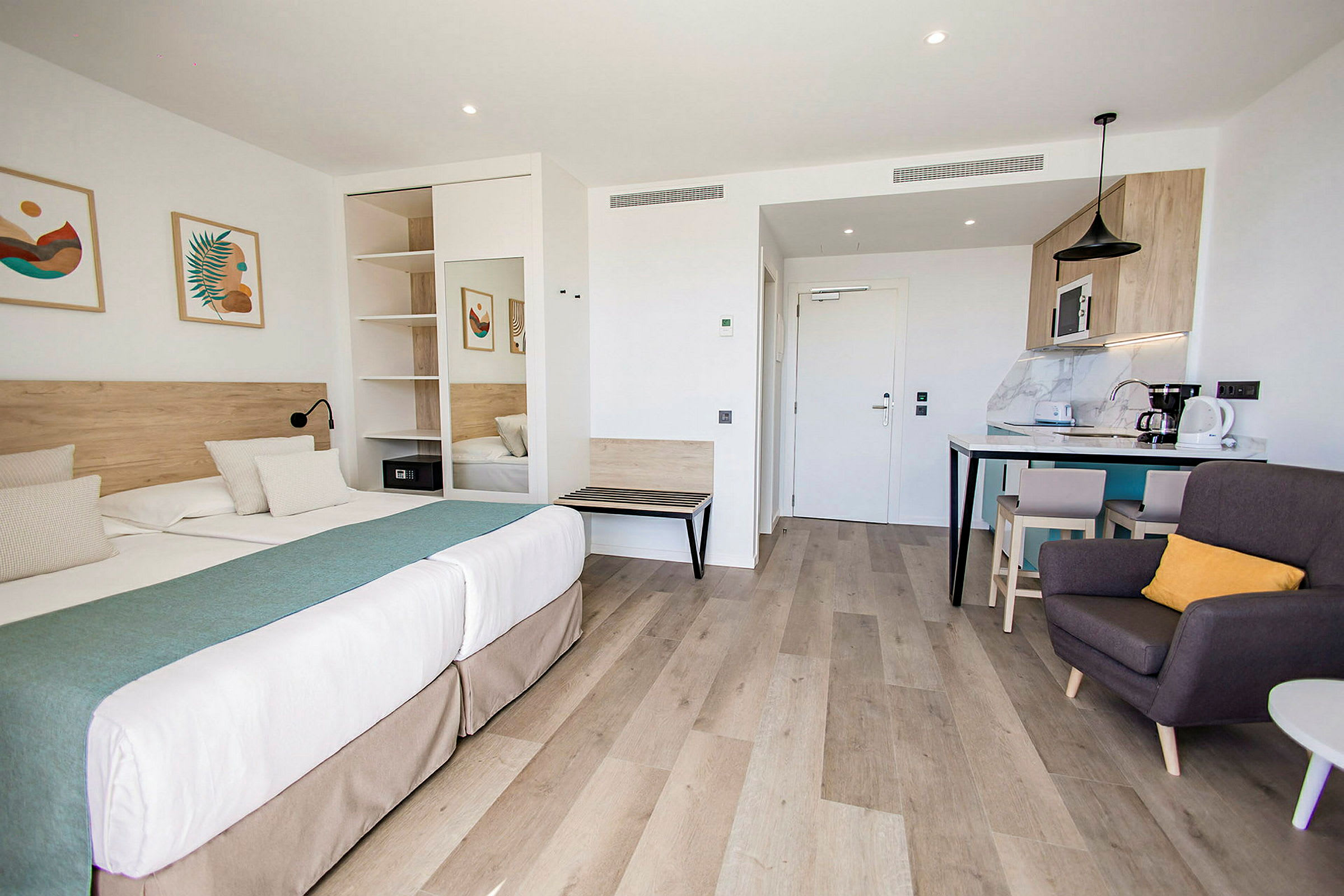 Et moderne hotellstudio med dobbeltseng, sittegruppe og kjøkkenkrok. (AI-generert tekst)